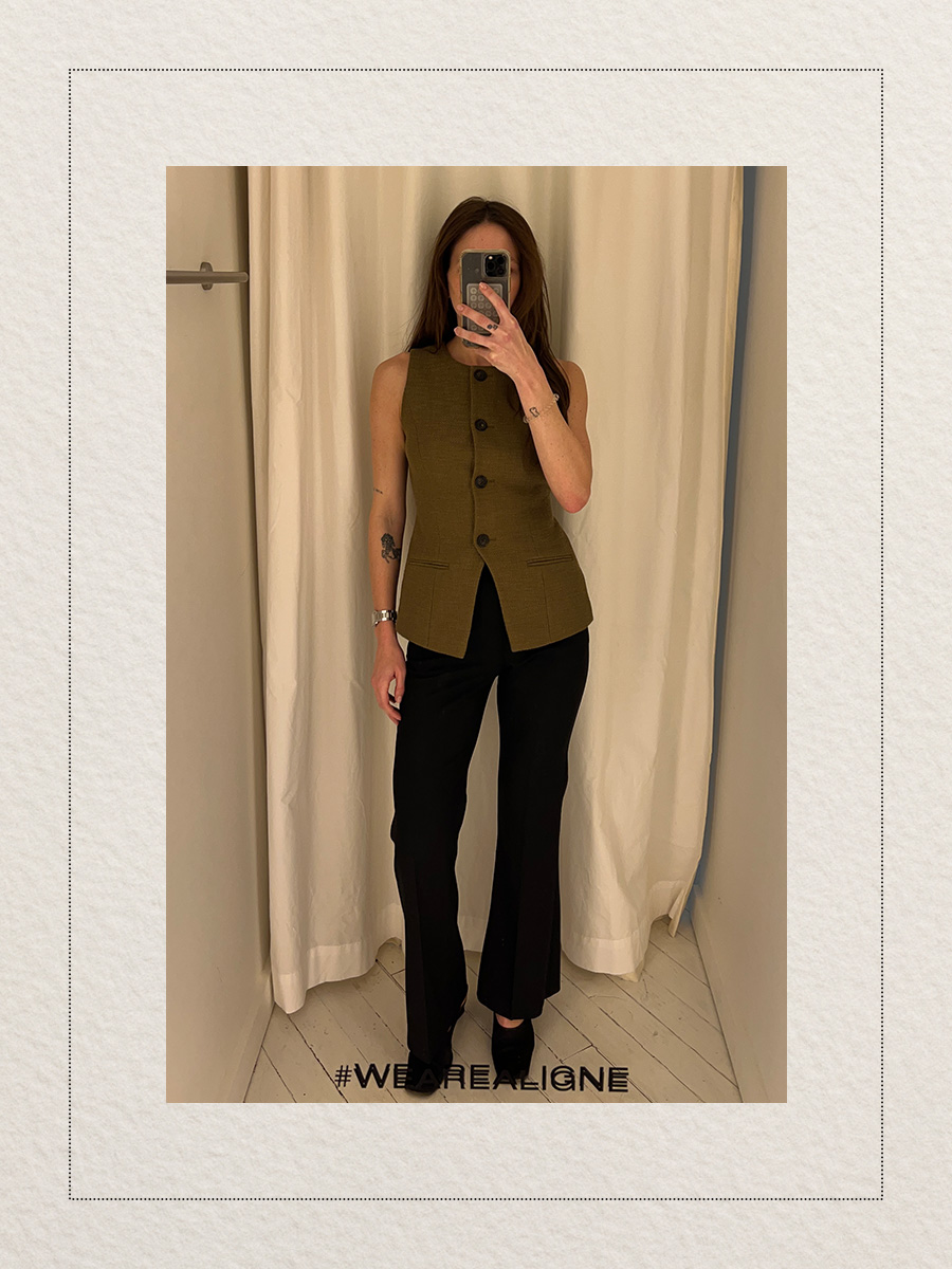Eliza Huber at the new Aligne pop-up store in New York City's SoHo district trying on a green vest and black flare trousers.