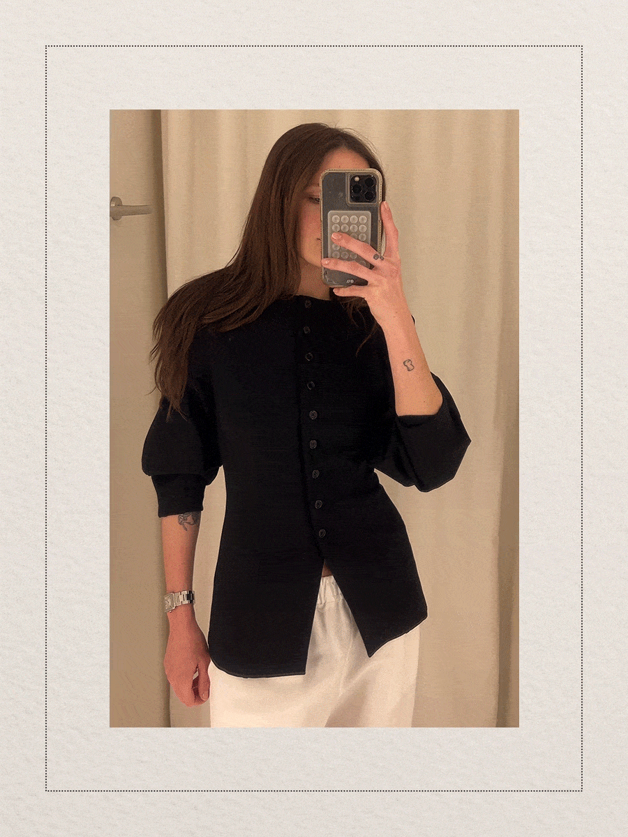 Eliza Huber at the new Aligne pop-up store in New York City's SoHo district trying on a sculpted knit cardigan with white linen pants.