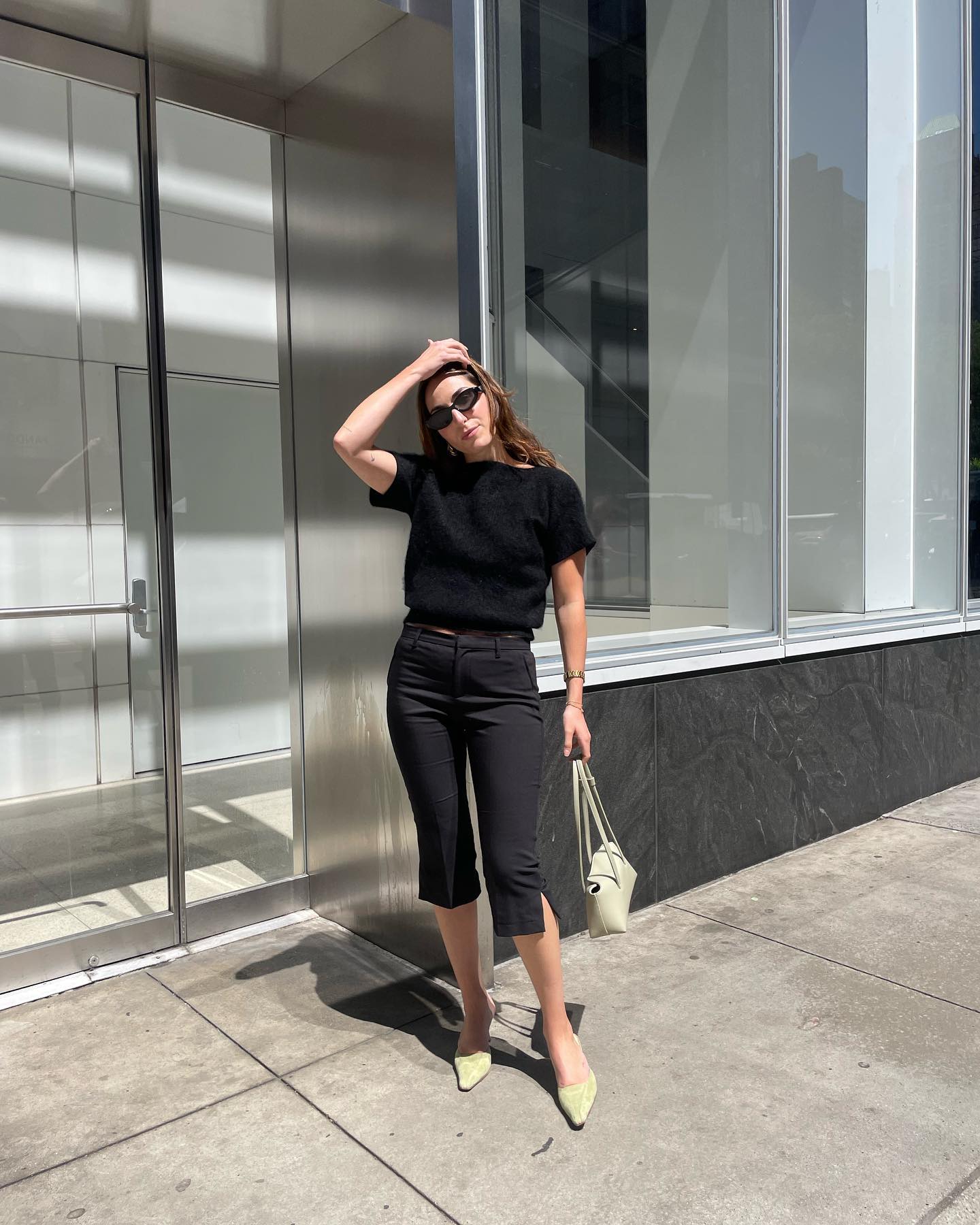 Anna wears a black tee, black capri pants, and beige muled heels.