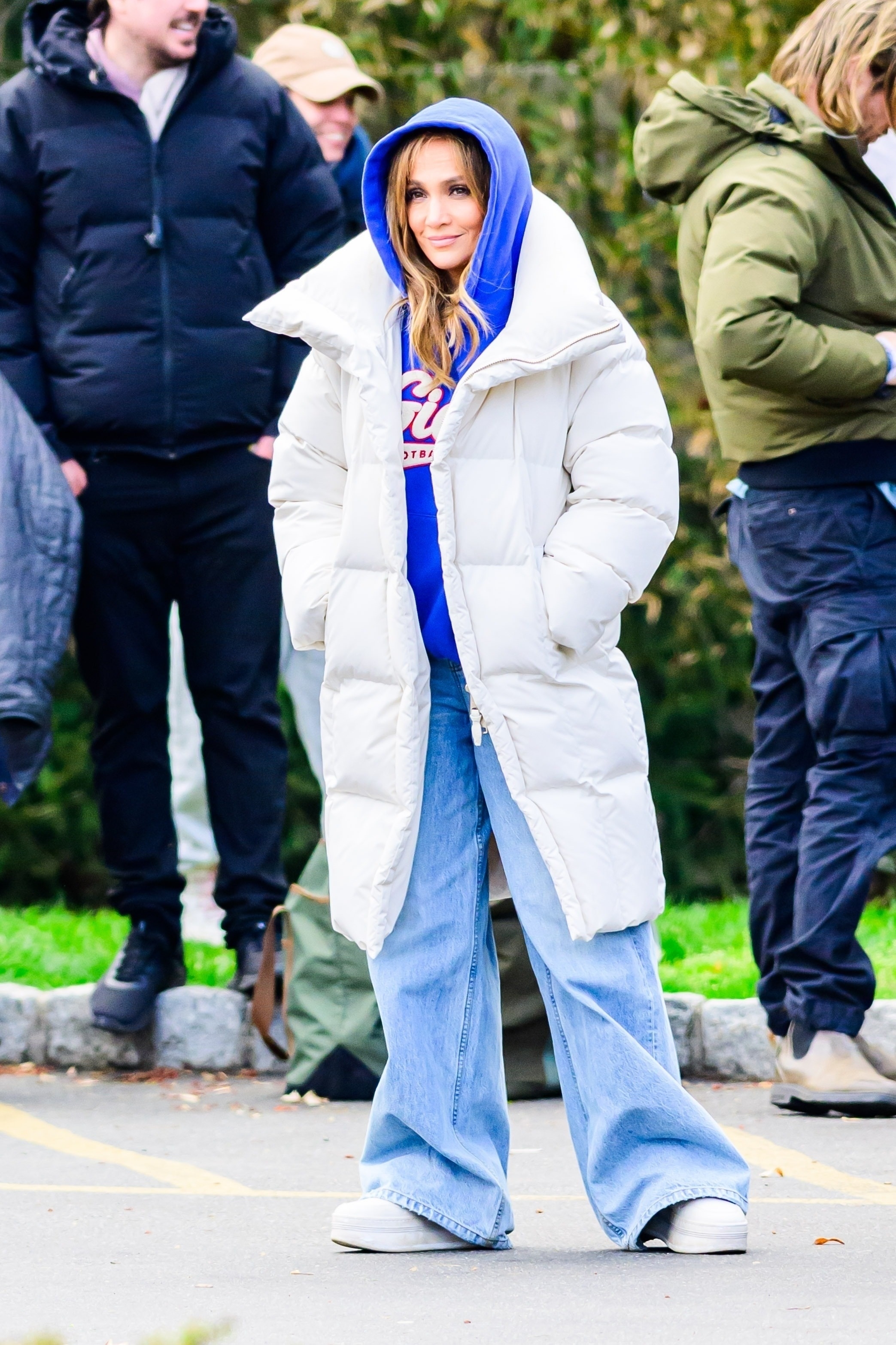 Jennifer Lopez wears DL1961 Razi jeans, a white puffer jacket, white sneakers, and a blue sweatshirt.