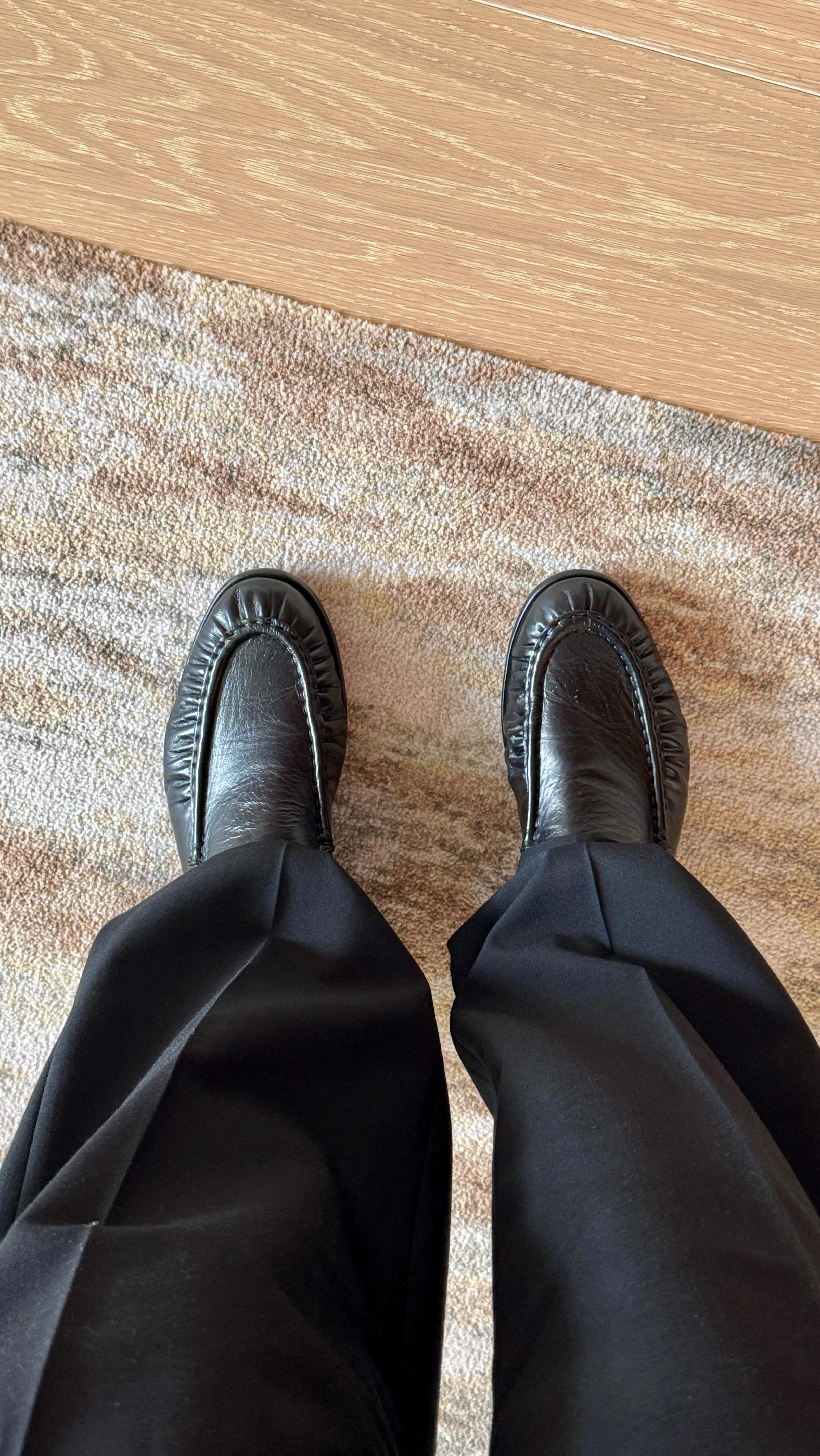 Bobby Schuessler wearing black ruched loafers and black trousers.