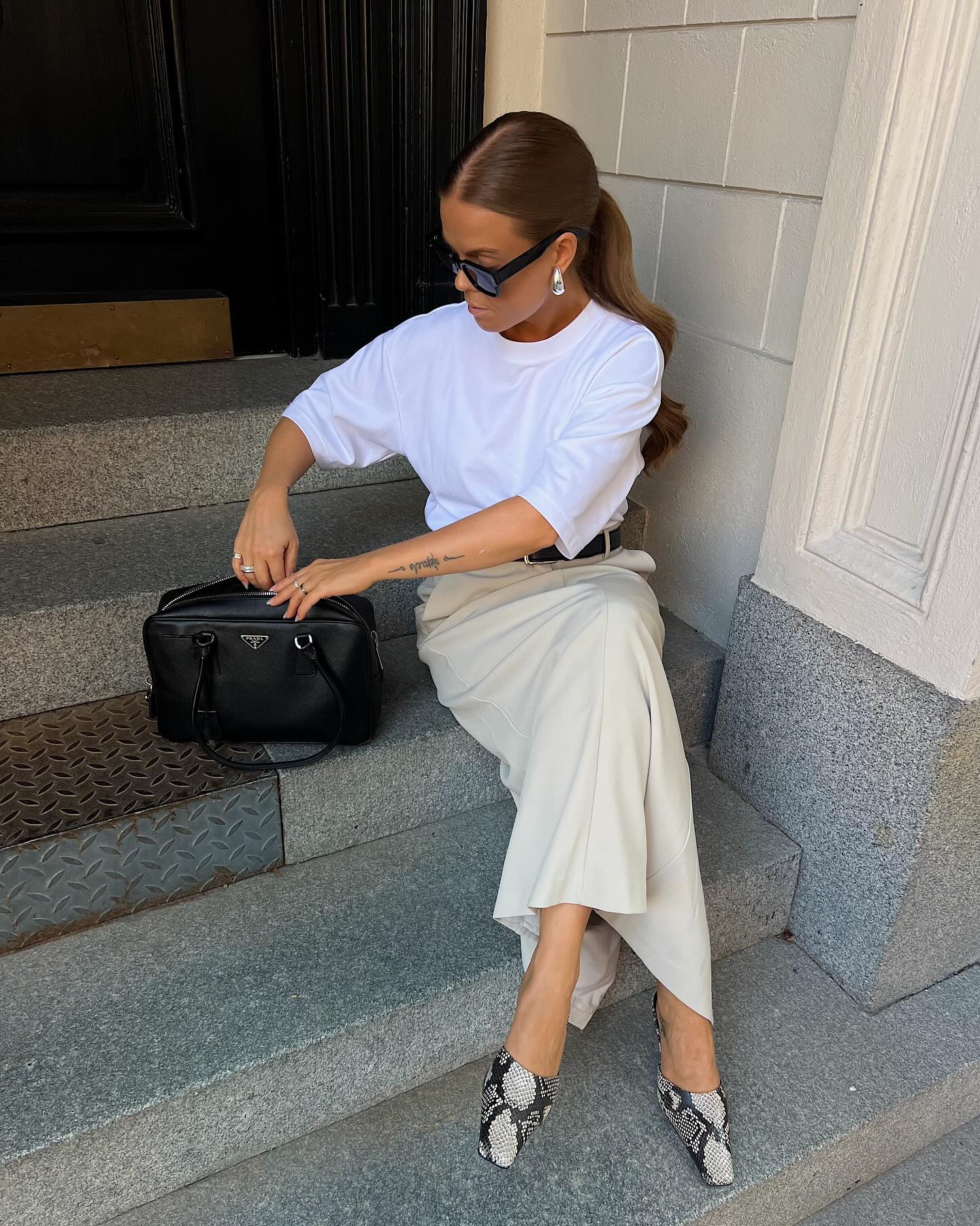 Stockholm Fashion Trends 2025: @haaannajohansson wears a pair of snake-print shoes with a beige linen skirt and white tee