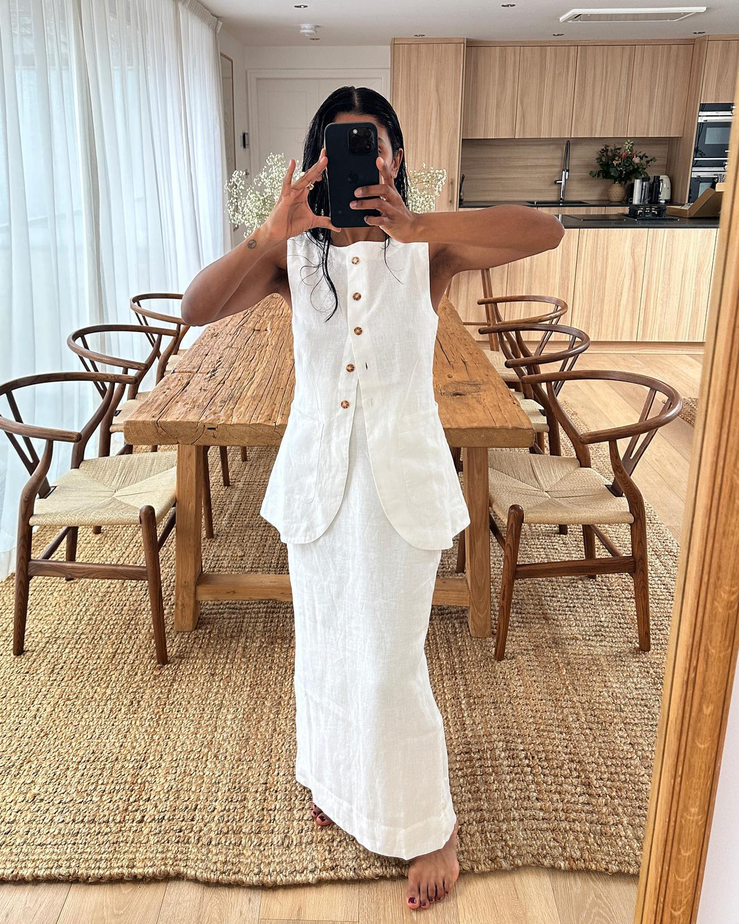 British style influencer Monikh Dale poses in a linen matching set with a button-front vest and maxi skirt in her chic London home