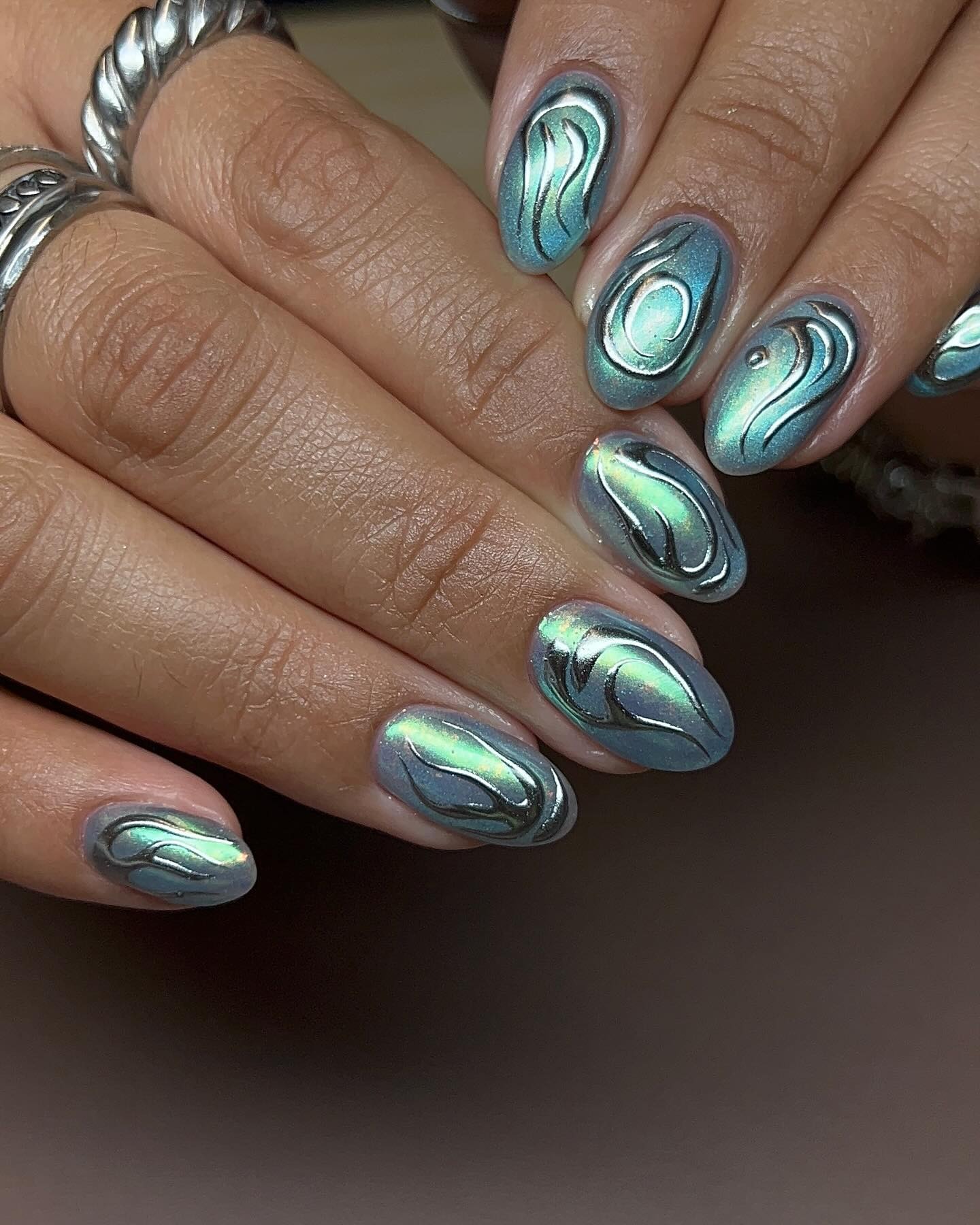Person with iridescent gel nails accented with swirling nail art.