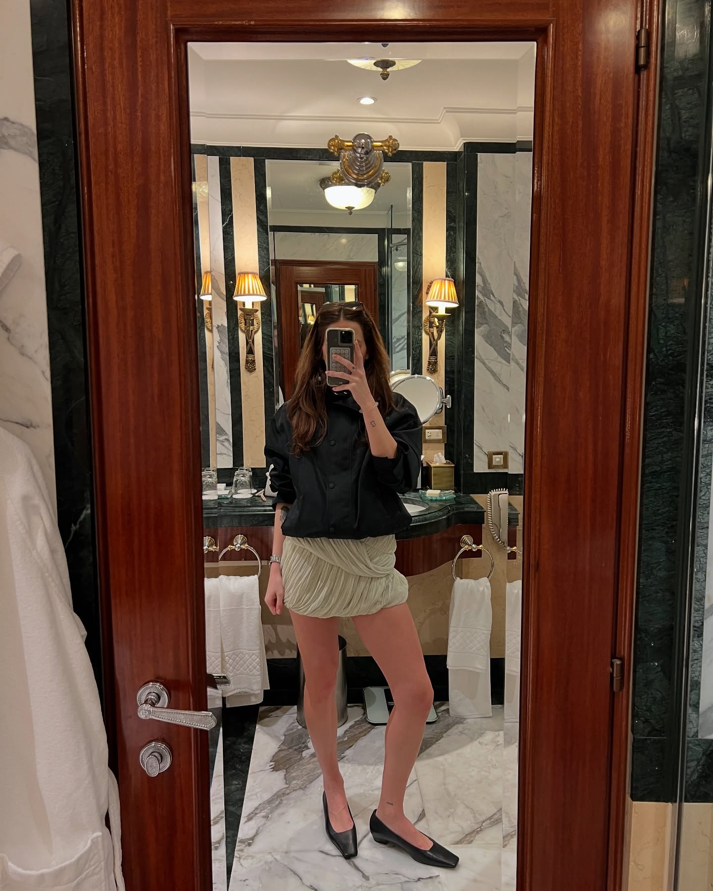 Eliza Huber wearing a black jacket, green skirt, and black COS flats.