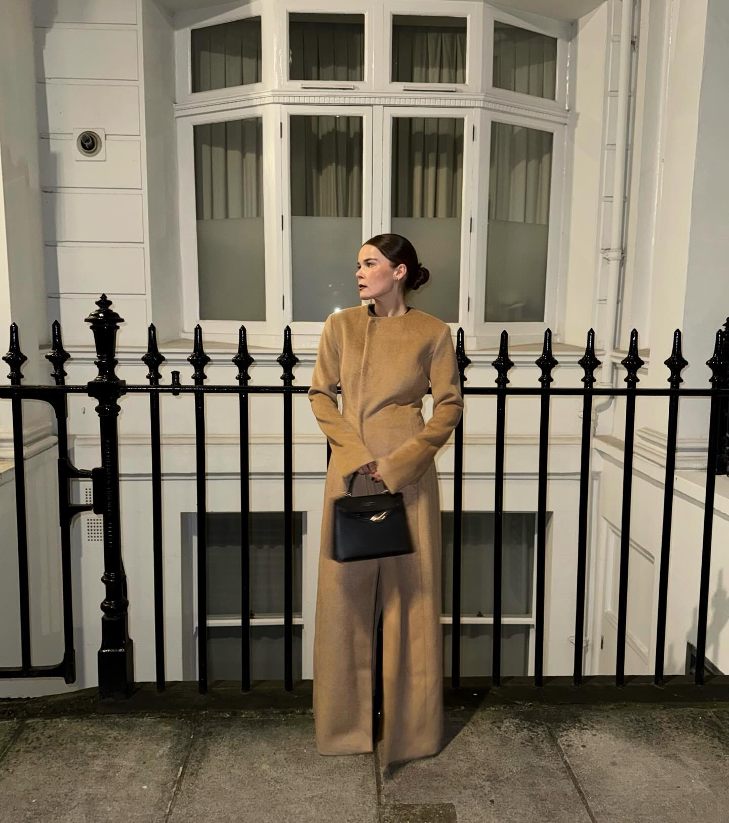 Rikke Krefting wearing a long tan coat with a black bag.