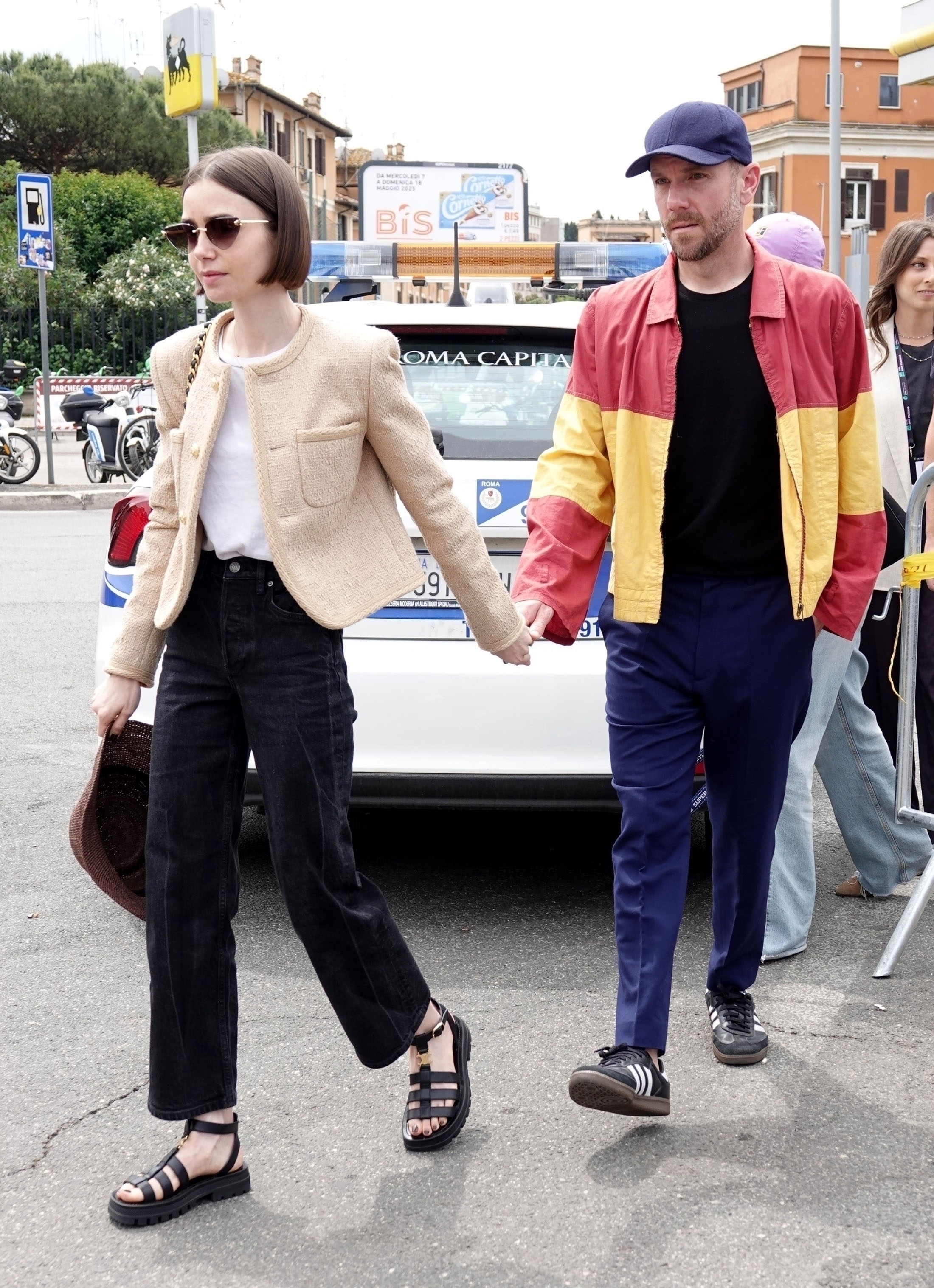 Lily Collins with her husband Charlie McDowell attending the Italian Open in Rome wearing a tan jacket and black Chanel bag with black jeans and Celine sandals.