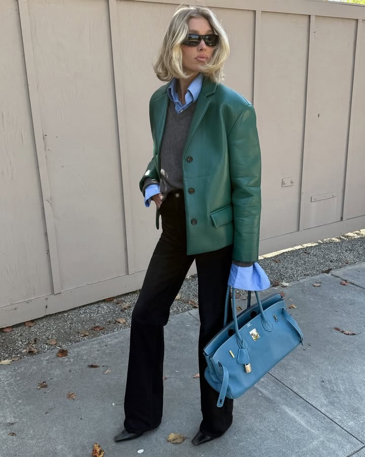Elsa Hosk posing with her hair in an effortless long bob, wearing a leather blazer, button-down, sweater, and pants.
