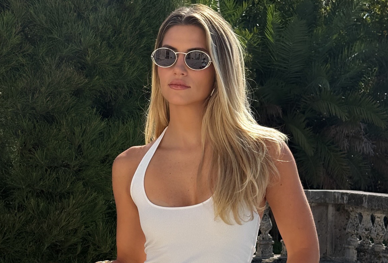 Woman wearing white halter top, sunglasses, and white shorts.