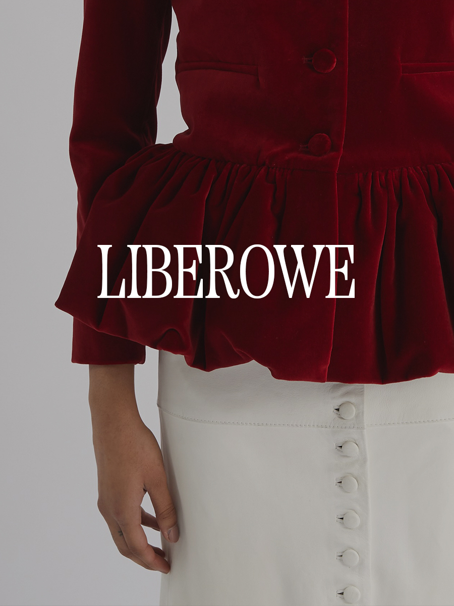 A photo of a model wearing a red velvet peplum jacket and leather skirt. Text says "Liberowe" in white capital serif letters.