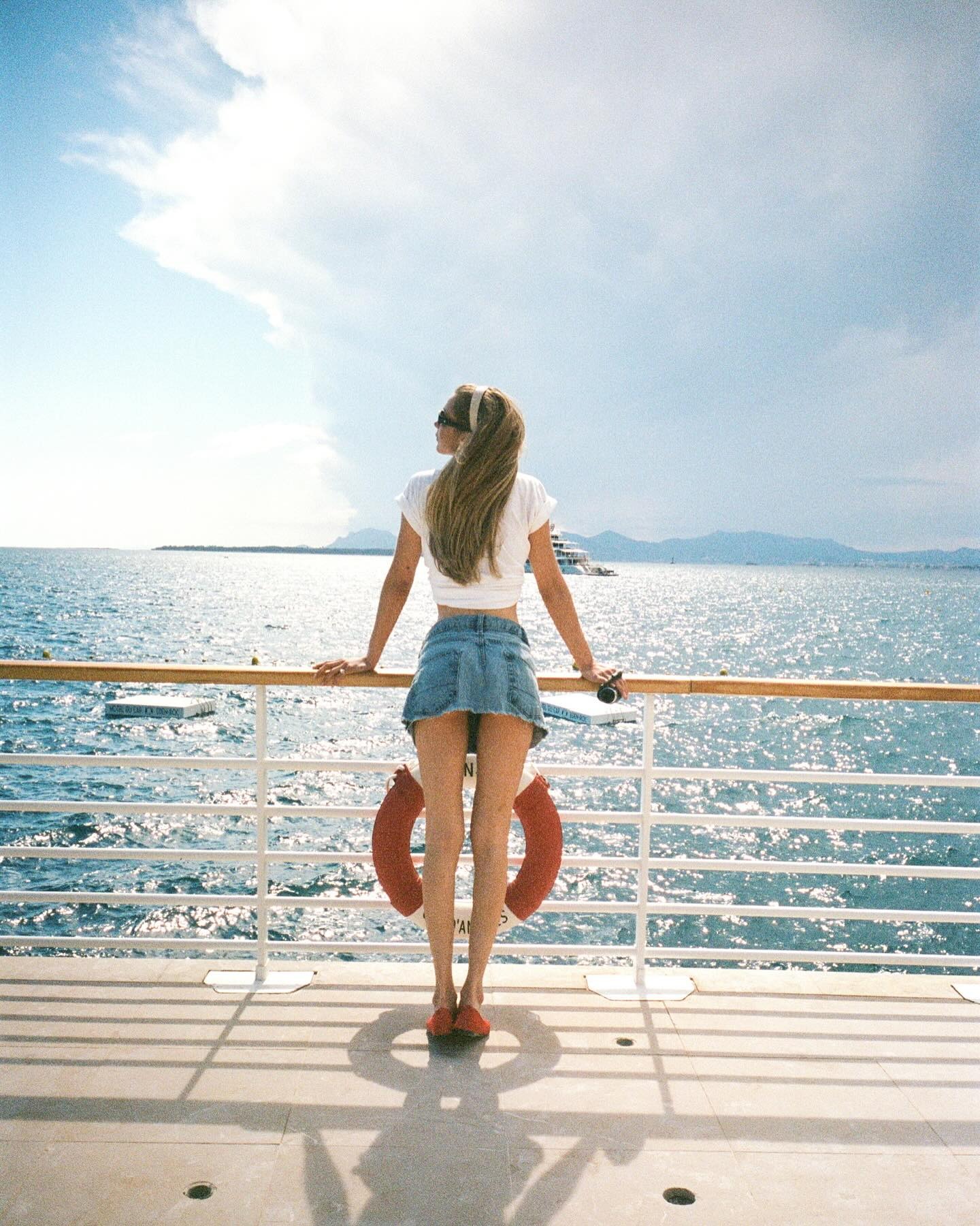 Bella Hadid wearing a white tee, denim skirt, and red ballet flats in Cannes