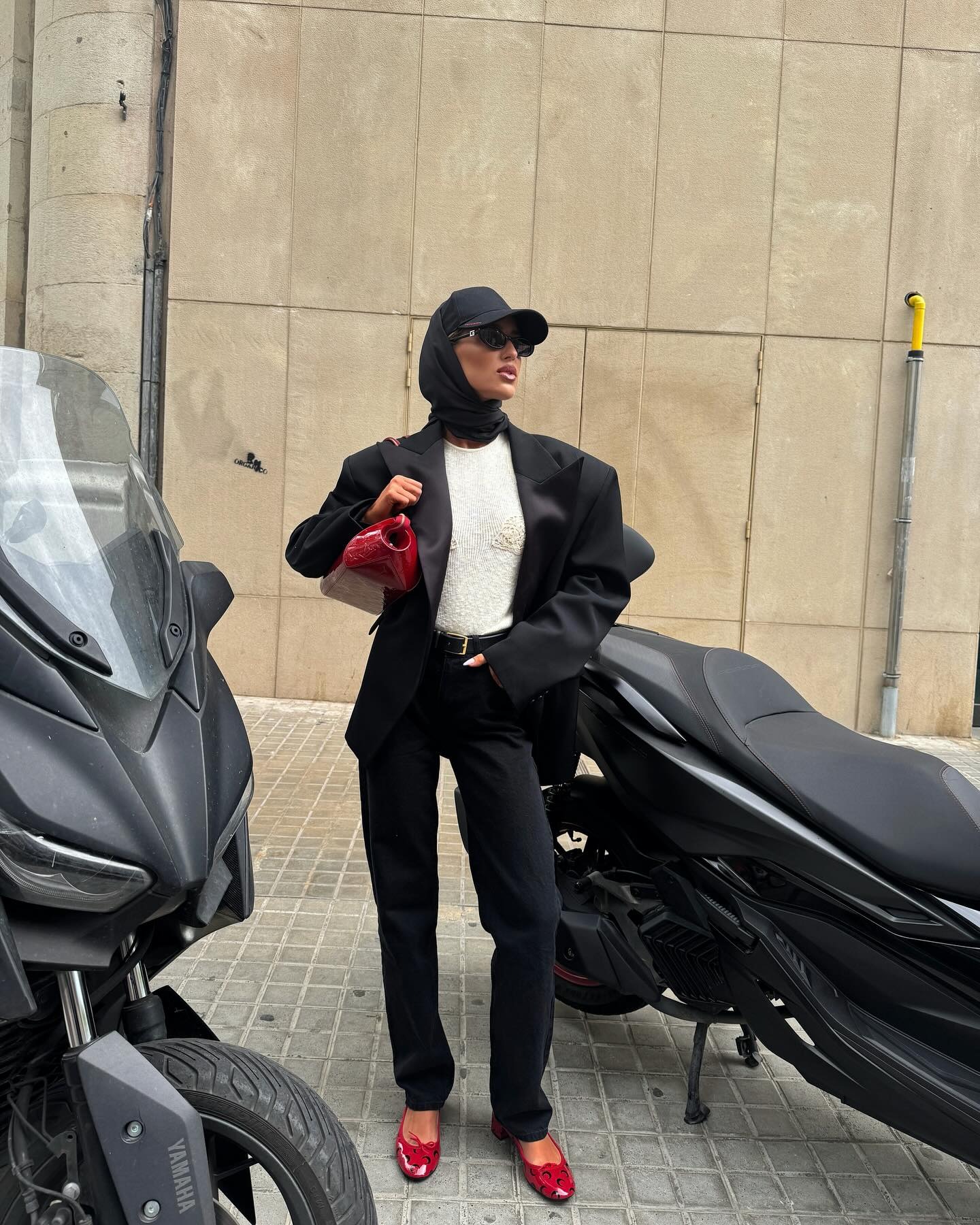 Emili Sindlev wearing a black outfit with red ballet flats