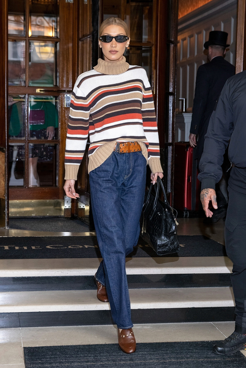 Bella Hadid wearing a striped sweater, dark denim jeans, and brown loafers in London