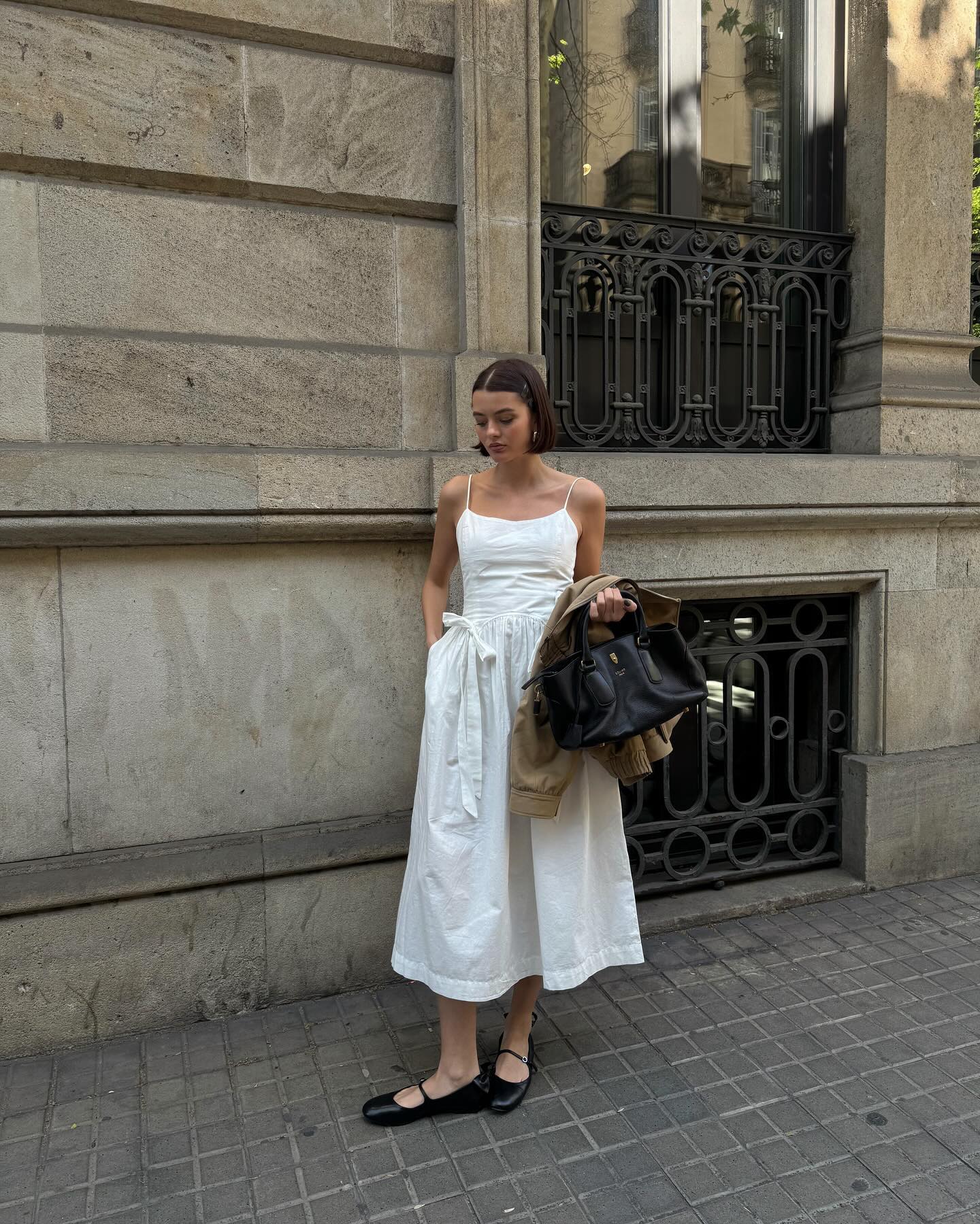 Mary L. Jean wears a white dress with bow details and black mary jane flats.