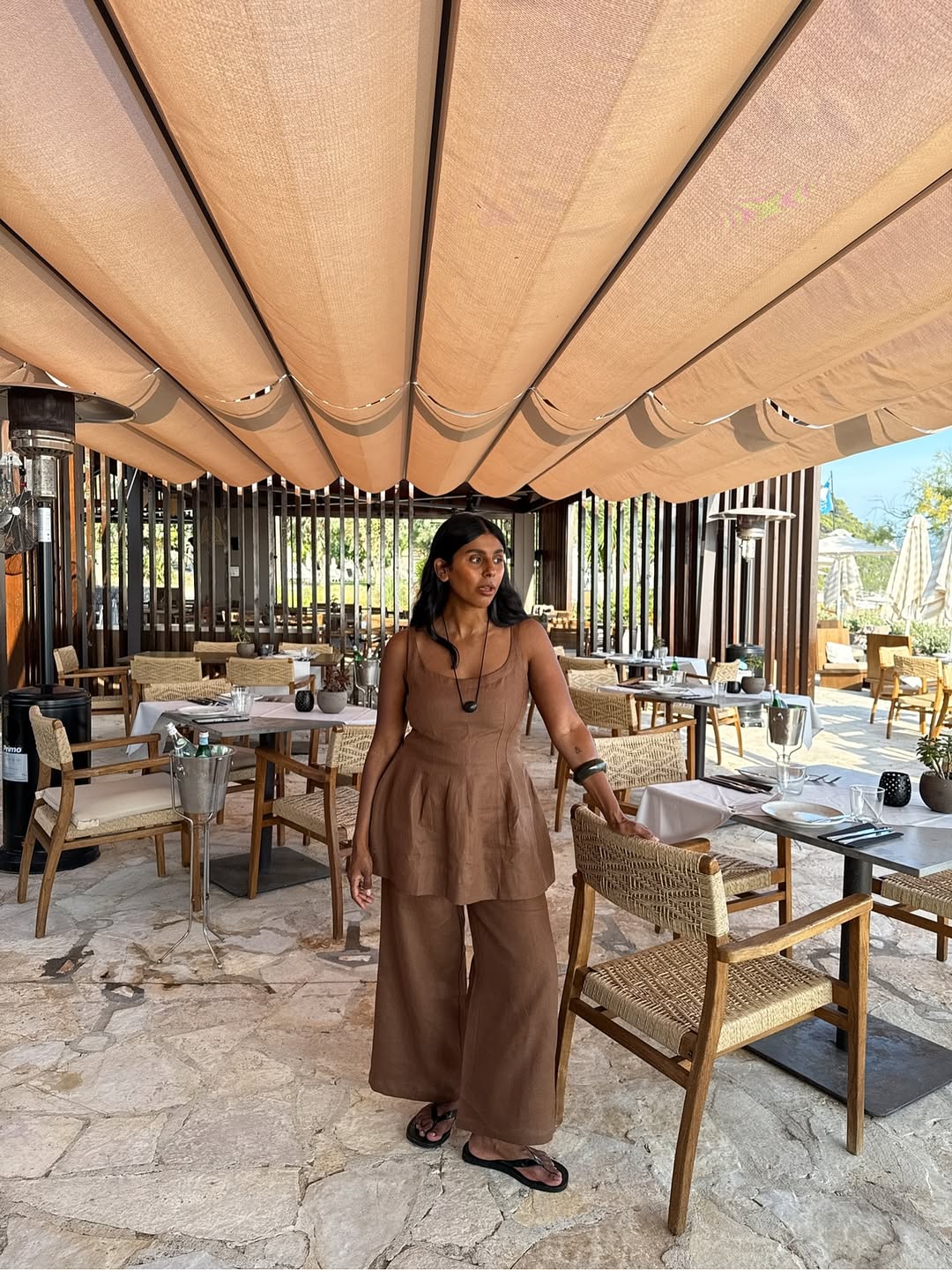 @monikh wears a cord necklace with a brown linen co-ord and black flip-flops
