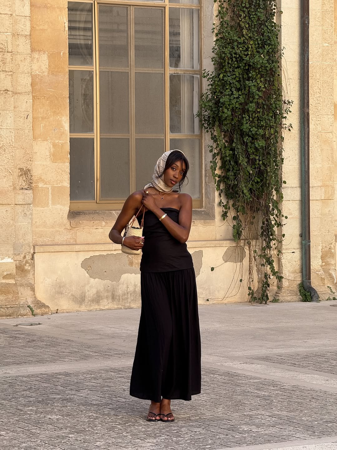 @emmanuellek_ wears a monochrome silk scarf with a black bandeau maxi dress, basket bag and mules