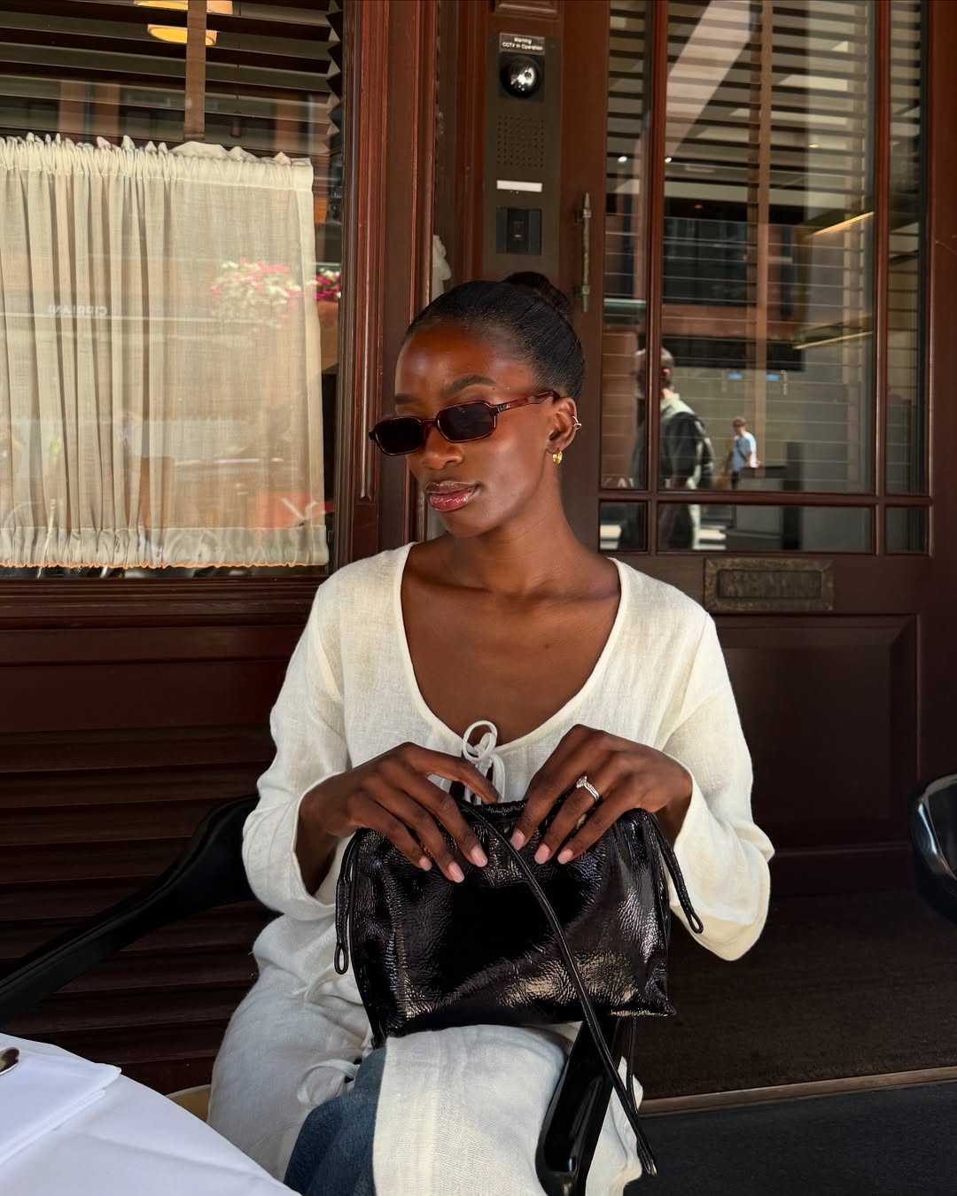 @_livmadeline wears rectangular sunglasses with white top, blue jeans, and leather bag