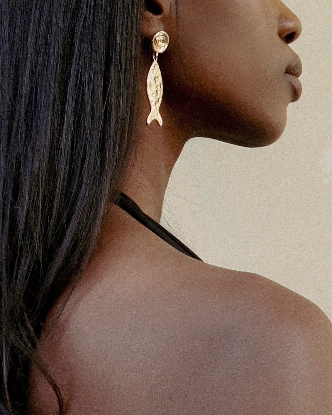French influencer Emmanuelle Koffi poses wearing Mango yellow gold textured sardine fish earrings