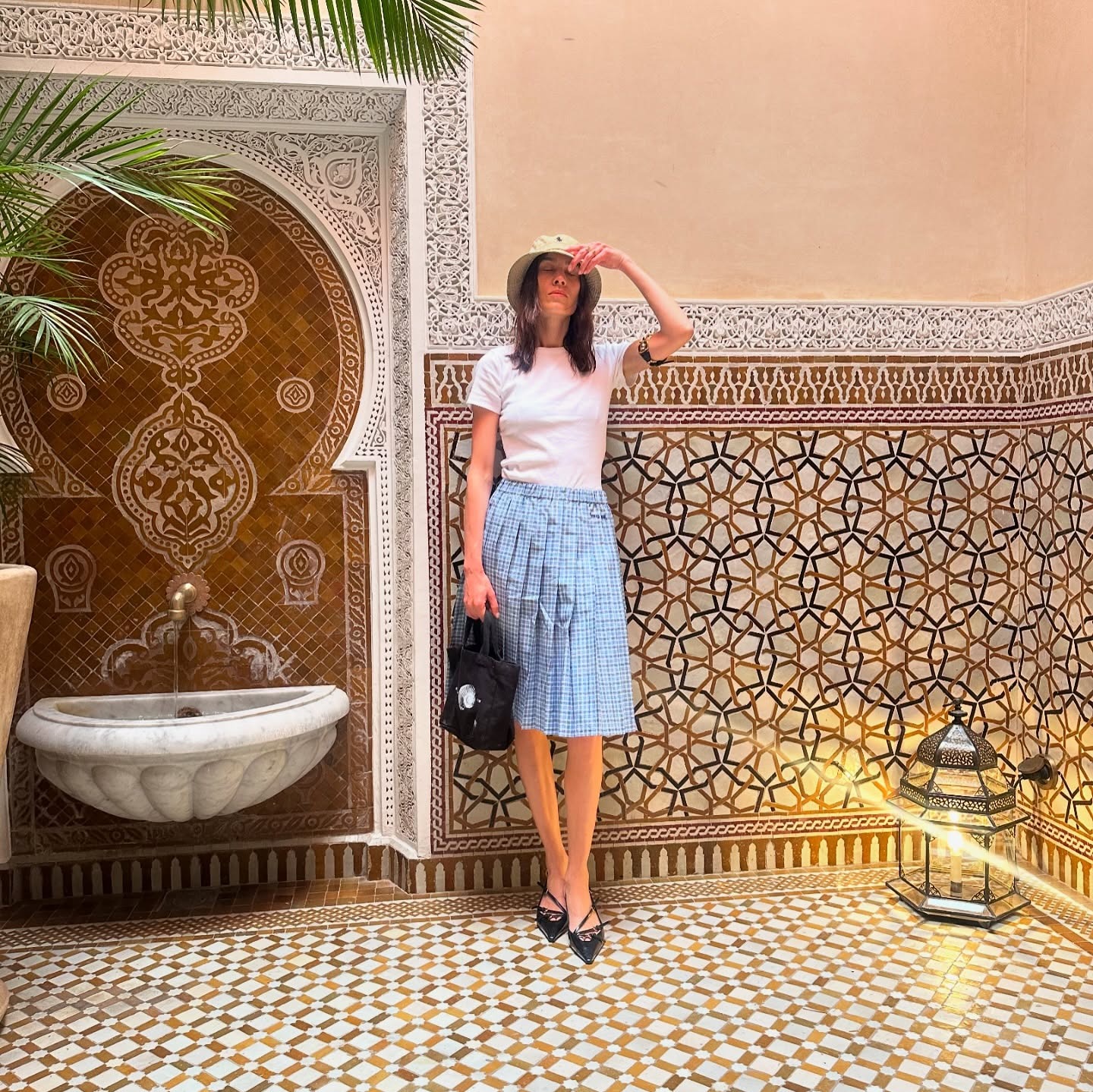 Alexa Chung wears a blue pleated skirt with a white t-shirt and Miu Miu buckle heels in Marrakesh.
