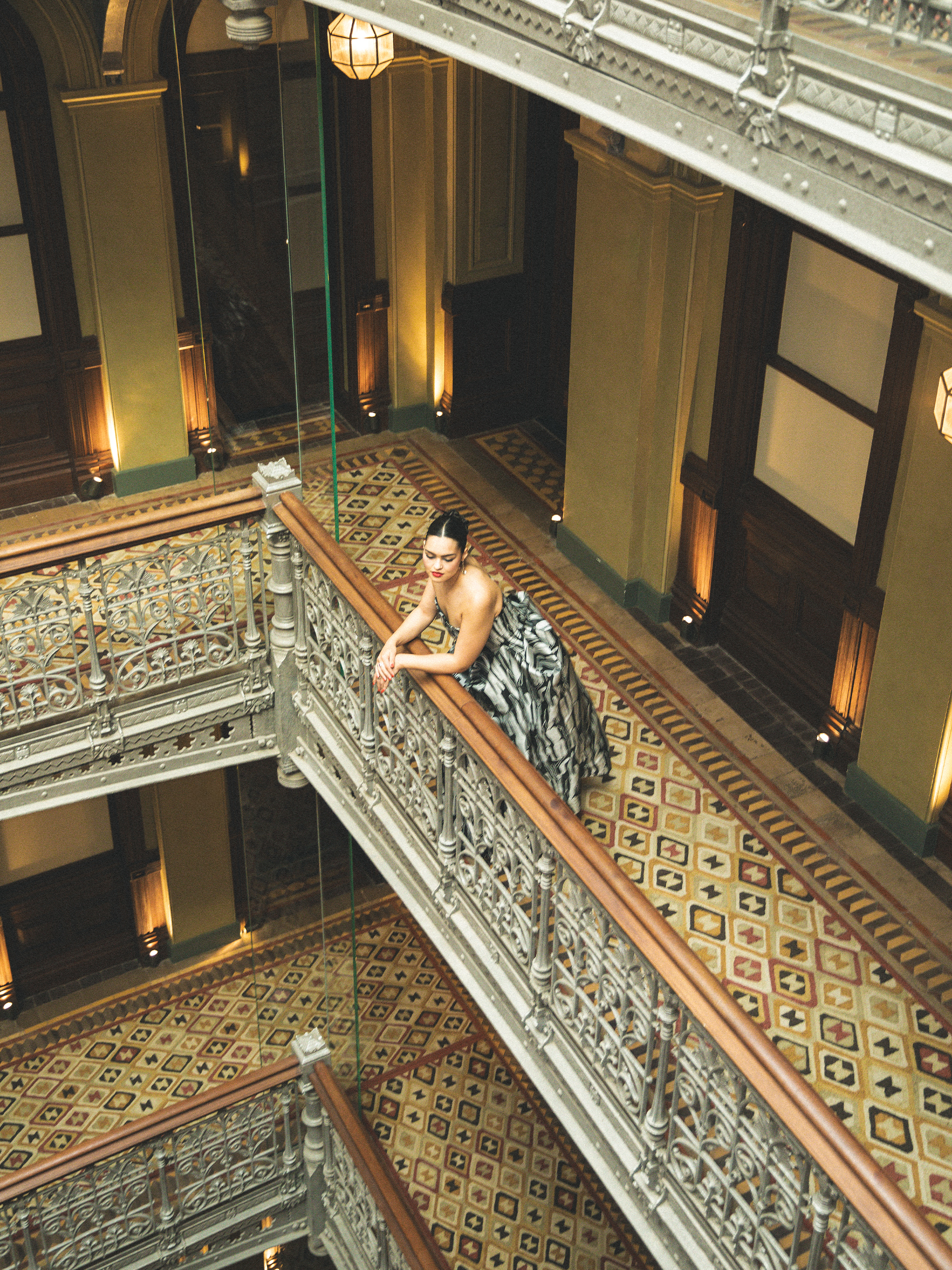 A birds-eye view photo of Anna Lambe leaning on the railing in her hotel.