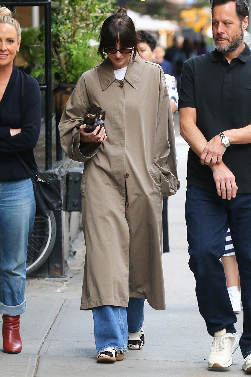Dakota Johnson wearing a trench coat, jeans, and Adidas cow sneakers in NYC