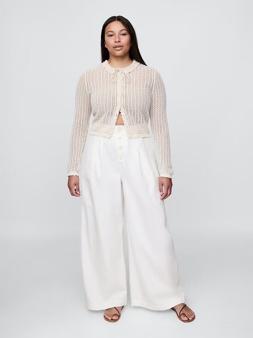 Woman wearing white pants and sheer button down shirt