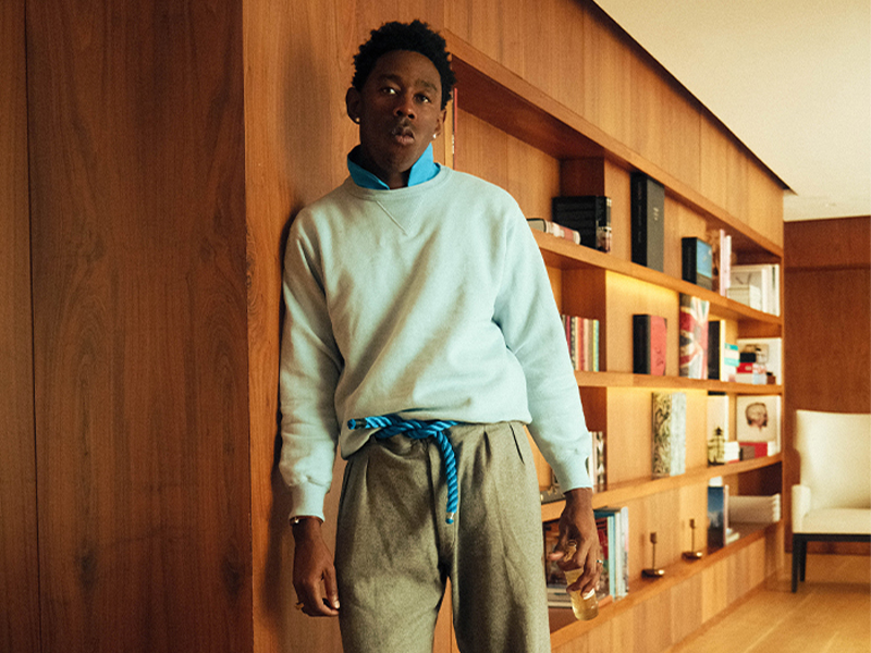 tyler wears white sweater, khaki slacks, and blue jogger sneaker