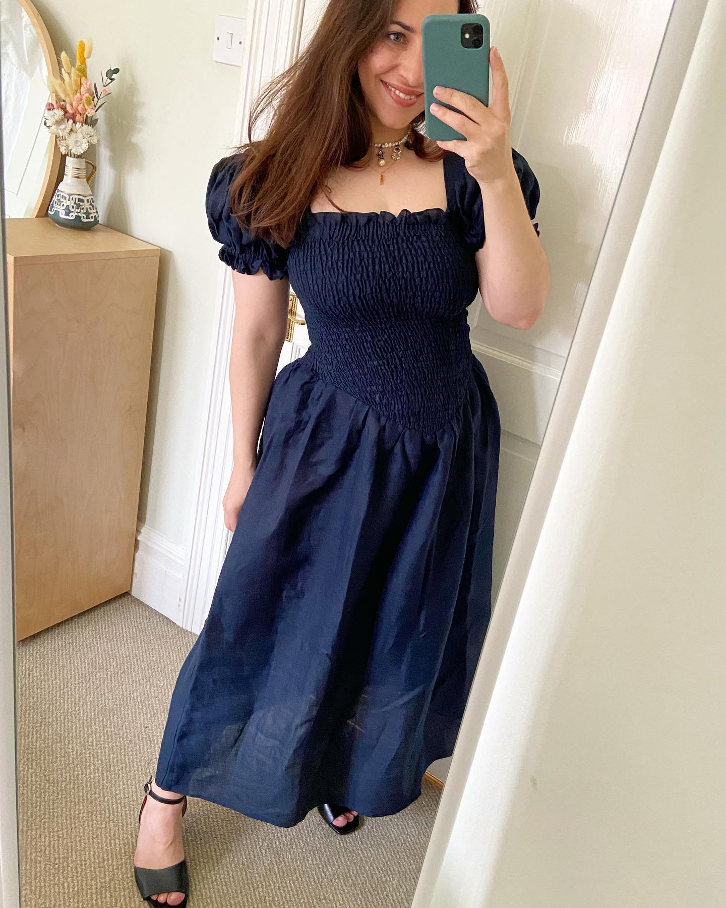 Who What Wear UK's Editor-in-Chief Hannah Almassi takes a mirror selfie indoors wearing a navy shirred dress from Sleeper.