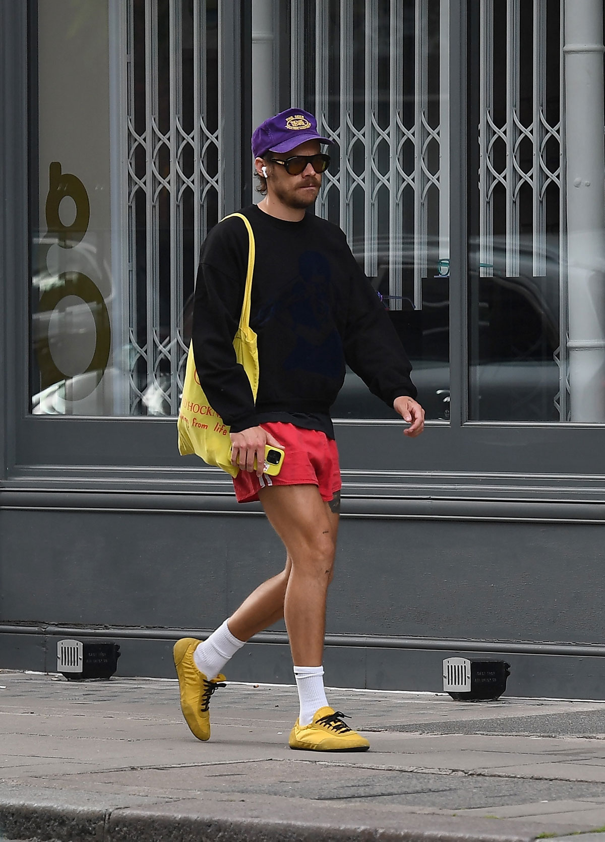 Harry Styles wearing red adidas short shorts and yellow Prada sneakers