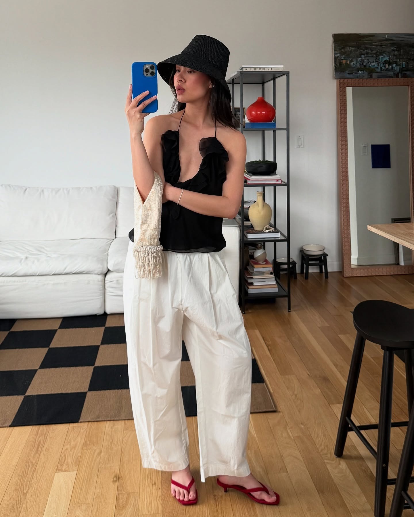 Influencer wears red kitten heel flip-flops with white trousers and an embellished black tank top.