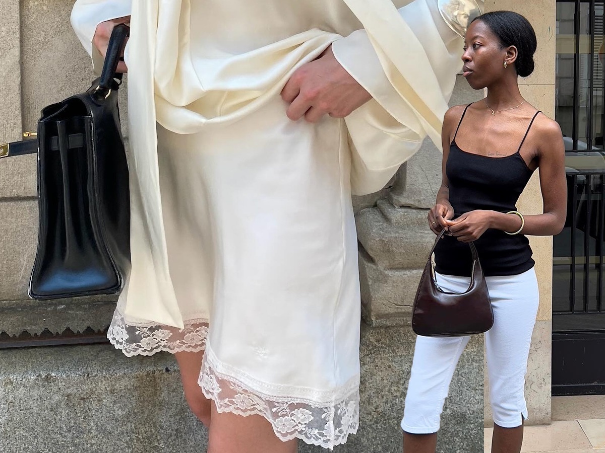 A woman in a white silk skirt. Another woman wearing white capris and a black tank top.