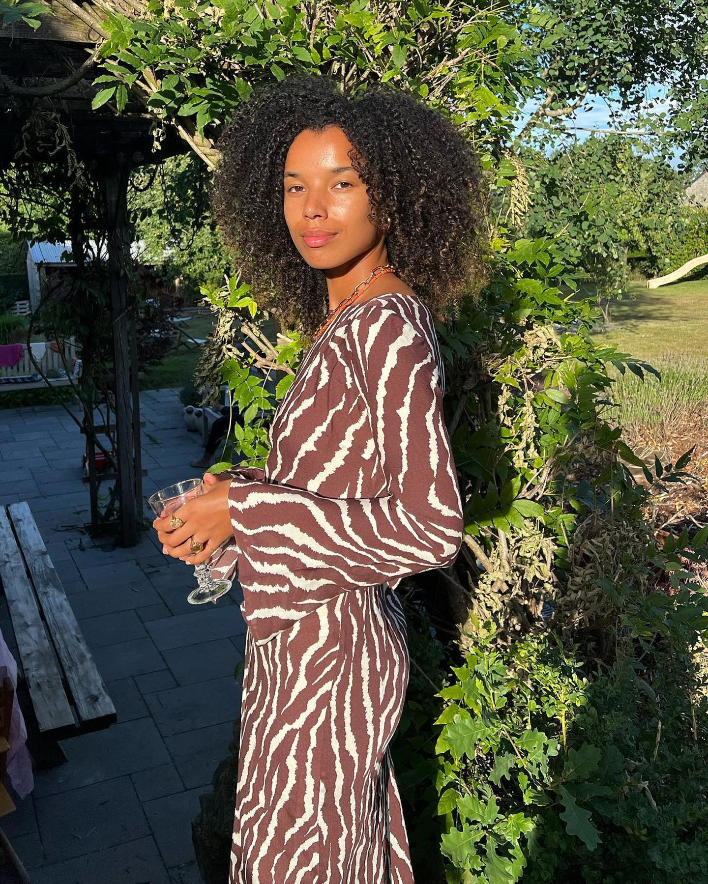 Dutch influencer Fia Hamelijnck poses in a garden wearing a Realisation Par animal print dress with long sleeves