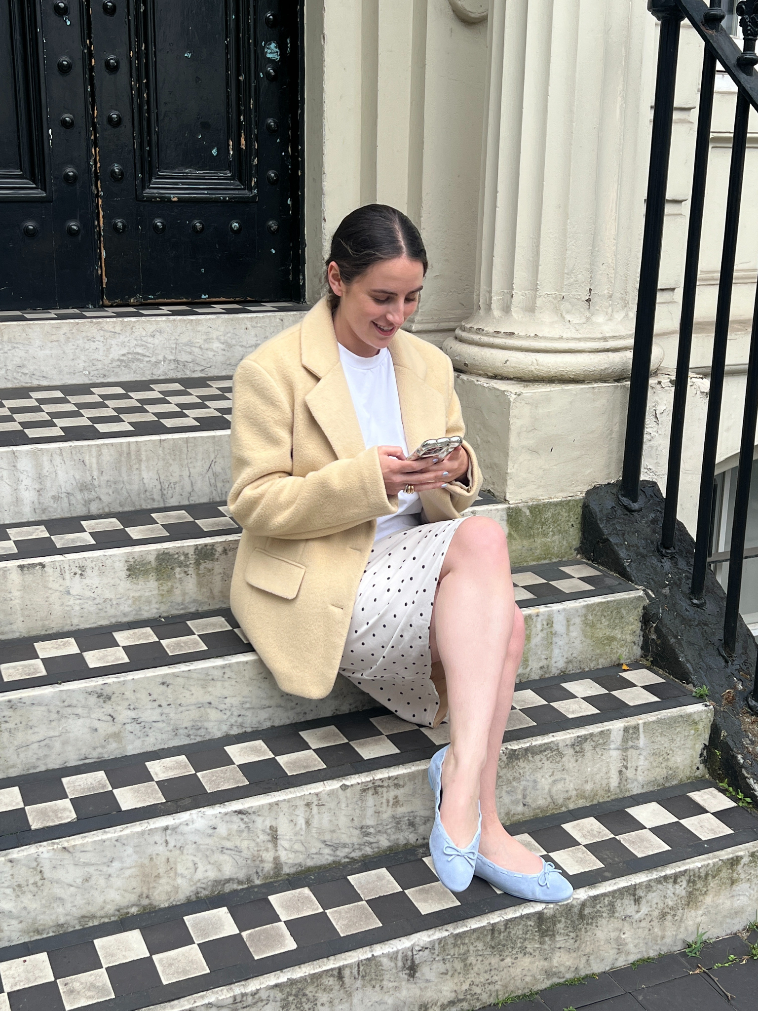 An image of Who What Wear UK's SEO writer Ava Gilchrist sitting on a stoop wearing the Reformation Suzanne Ballet flats.
