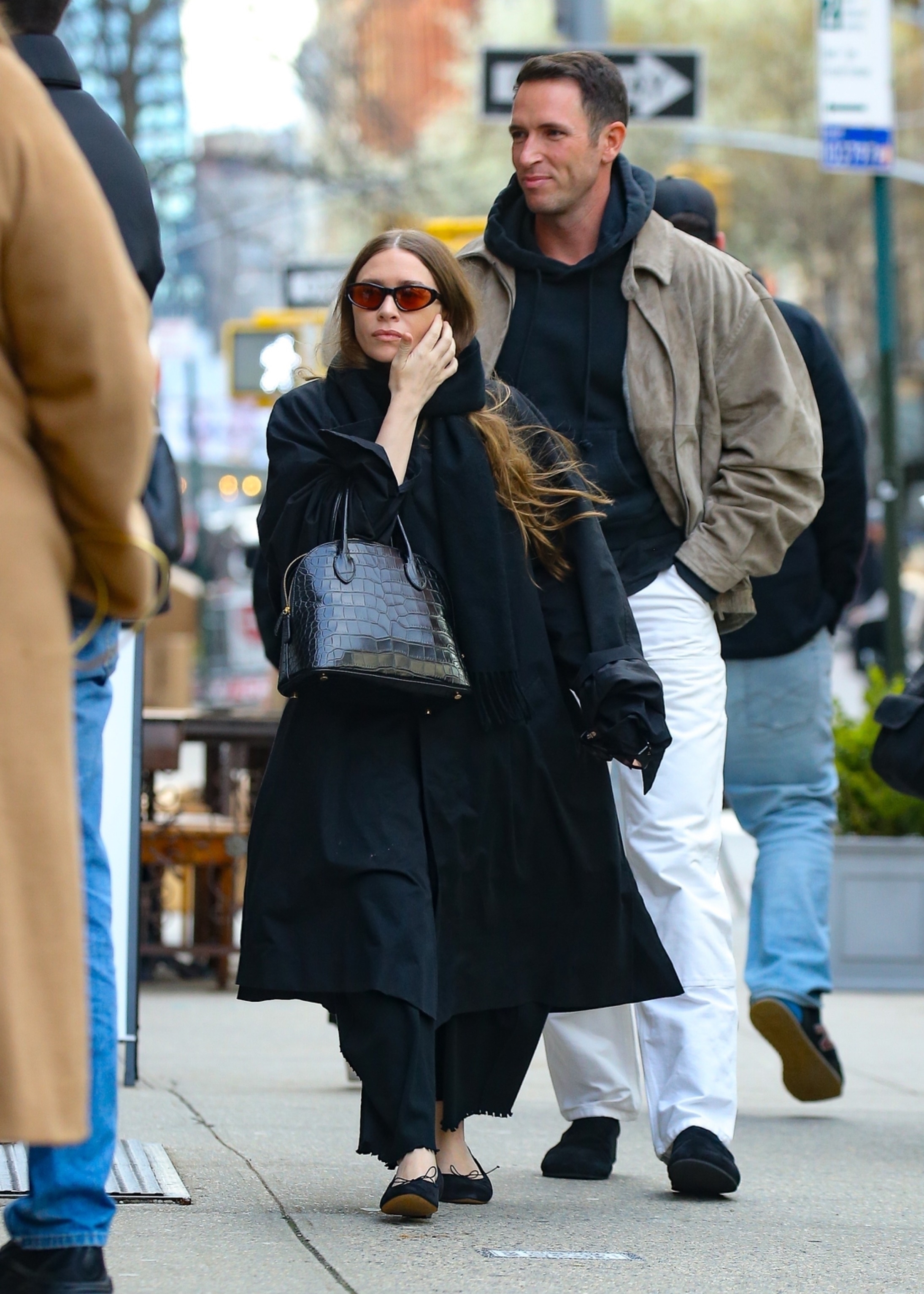 Ashley Olsen in a long coat, black dress, black The Row Lady Bag, and ballerina flats in New York City with the brand's Vice President Brand Identity Marketing, Nicolas Turko.
