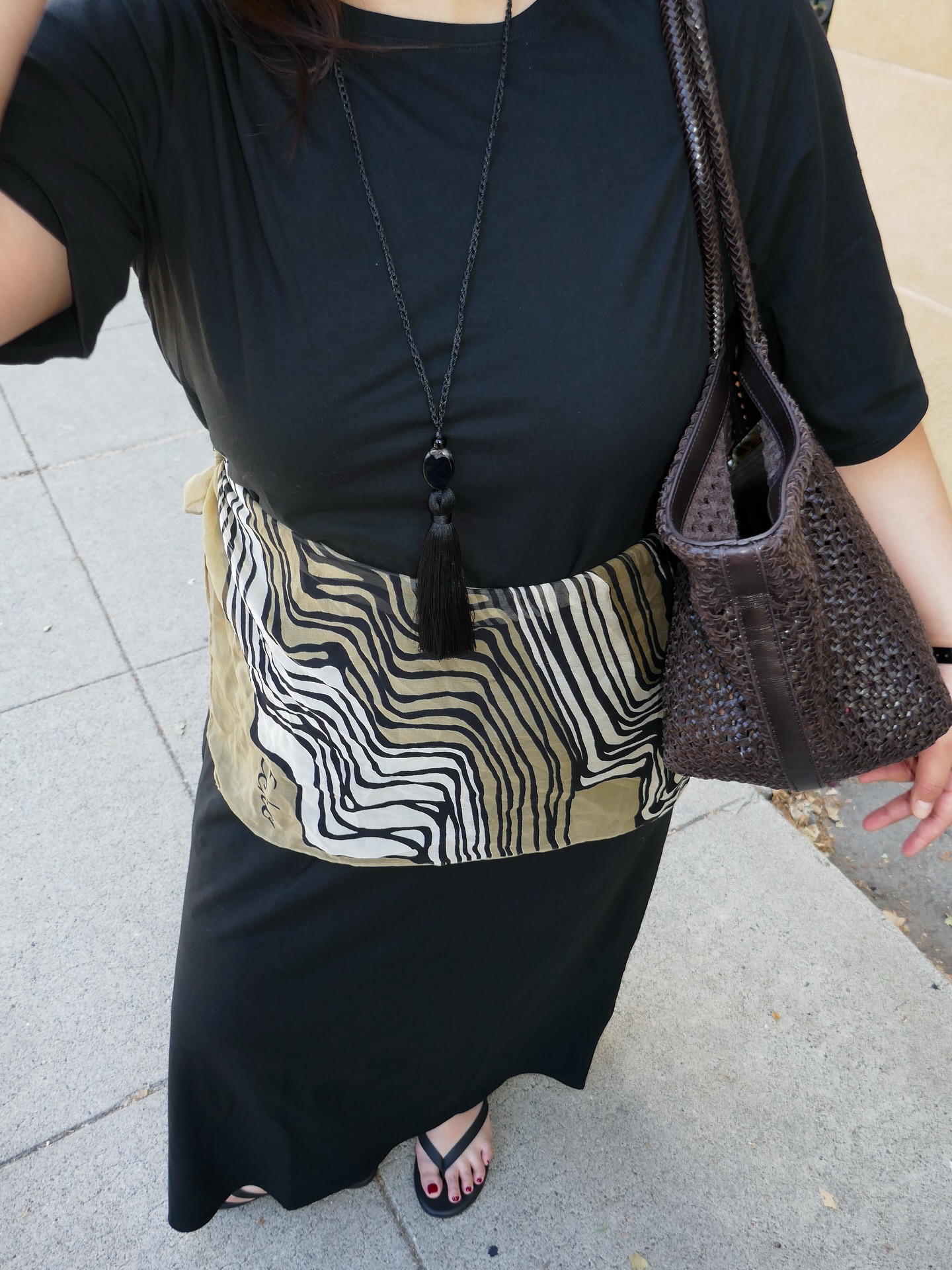 An image of @marina_torres wearing a black waisted dress with a rope necklace.