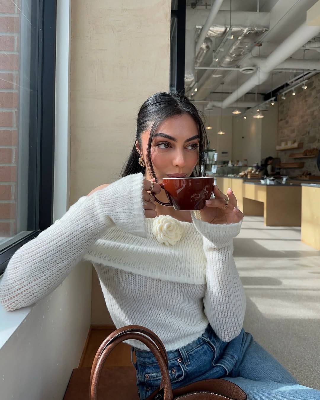 Mobina Peiman wears a white sweater with a peony detail while visiting a coffee shop