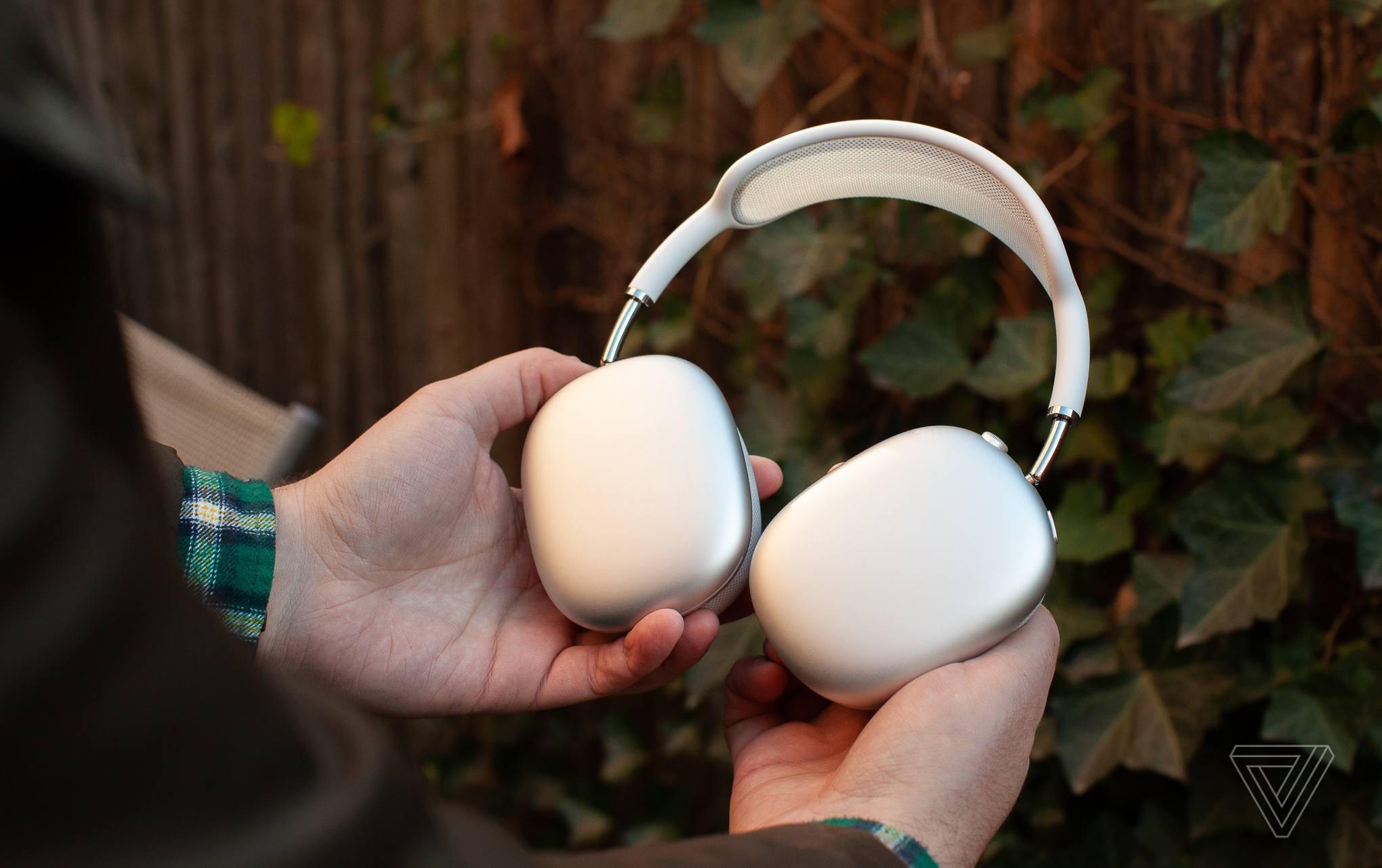 Hands holding the silver Apple AirPods Max.