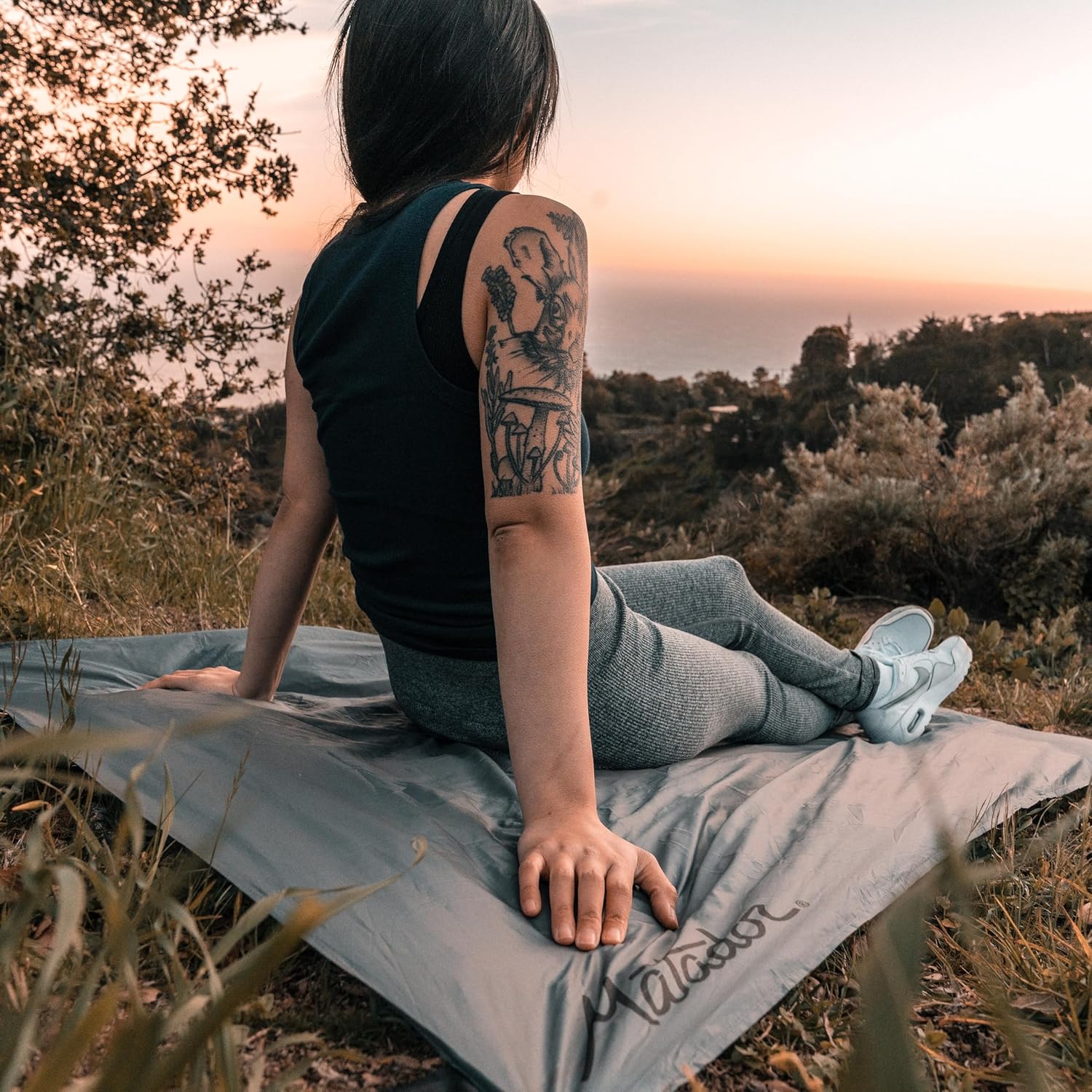 Person sitting on silvery fold-out blanket in k