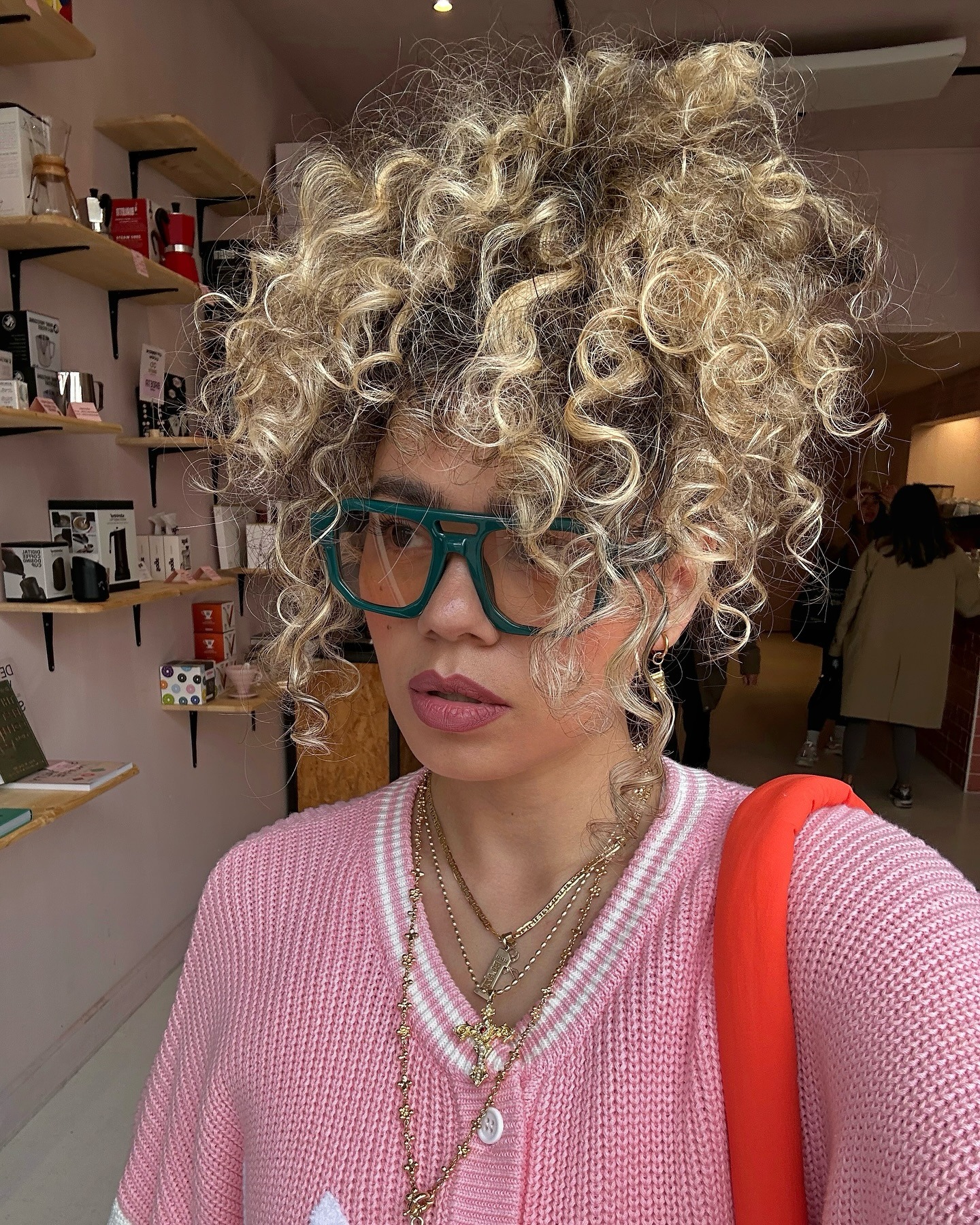 A woman with curly hair styled in an updo, with natural roots and bright blonde ends