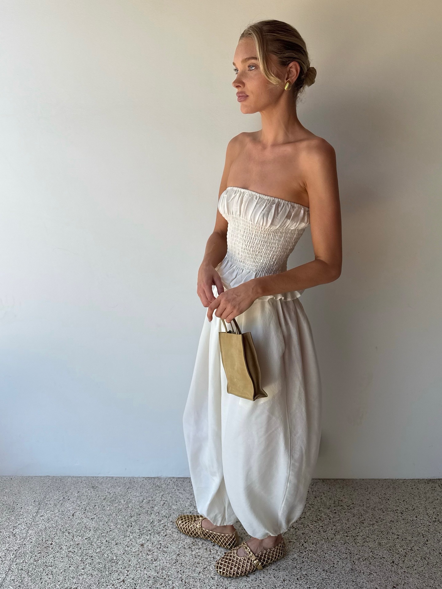 Elsa Hosk wearing a white jumpsuit and The Row Small To Go Bag.