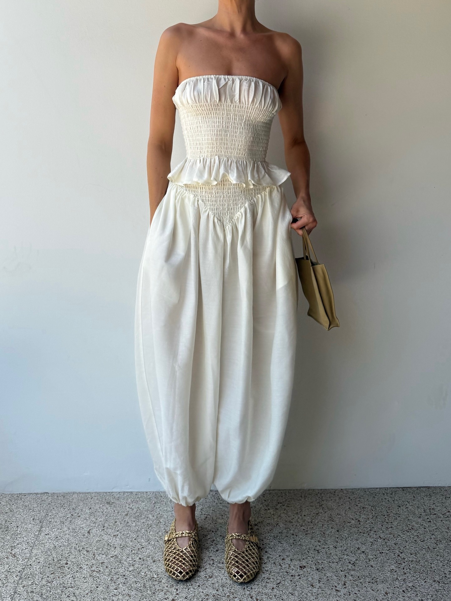 Elsa Hosk wearing a white jumpsuit and The Row Small To Go Bag.