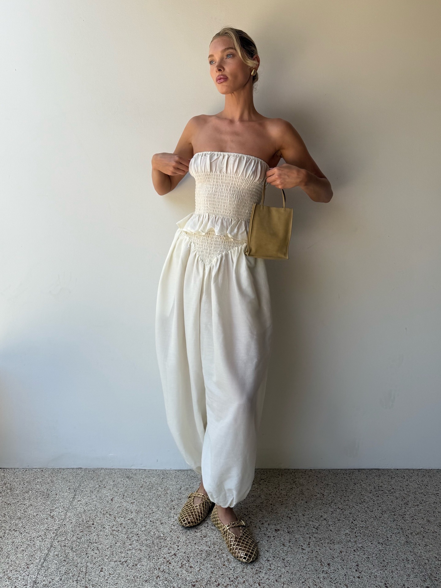 Elsa Hosk wearing a white jumpsuit and The Row Small To Go Bag.