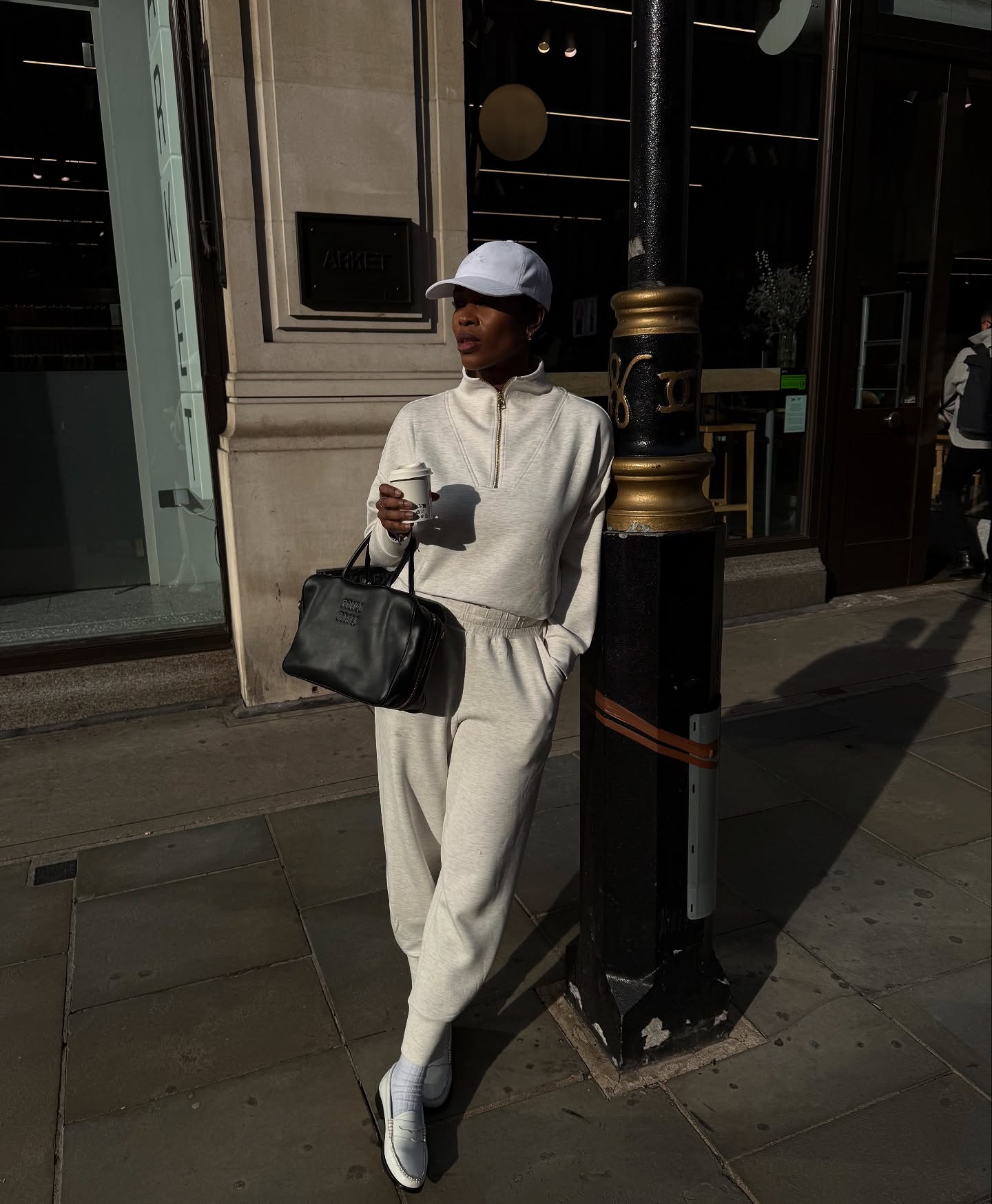 @nlmarilyn wears a knitted jumper and trouser outfit with loafers and a baseball cap