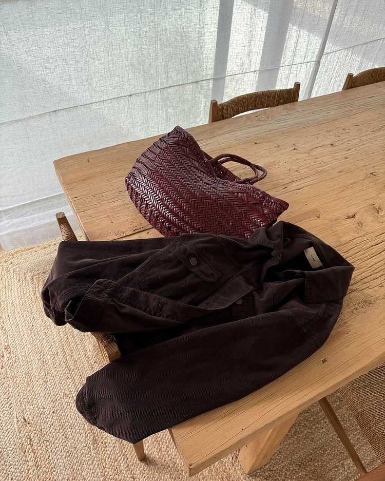 @monikh shares her burgundy woven leather basket bag as it lies on a wooden table