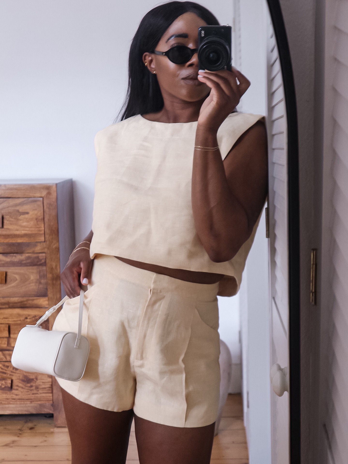 @_loissterling wears a butter yellow top and matching shorts with a white leather mini bag