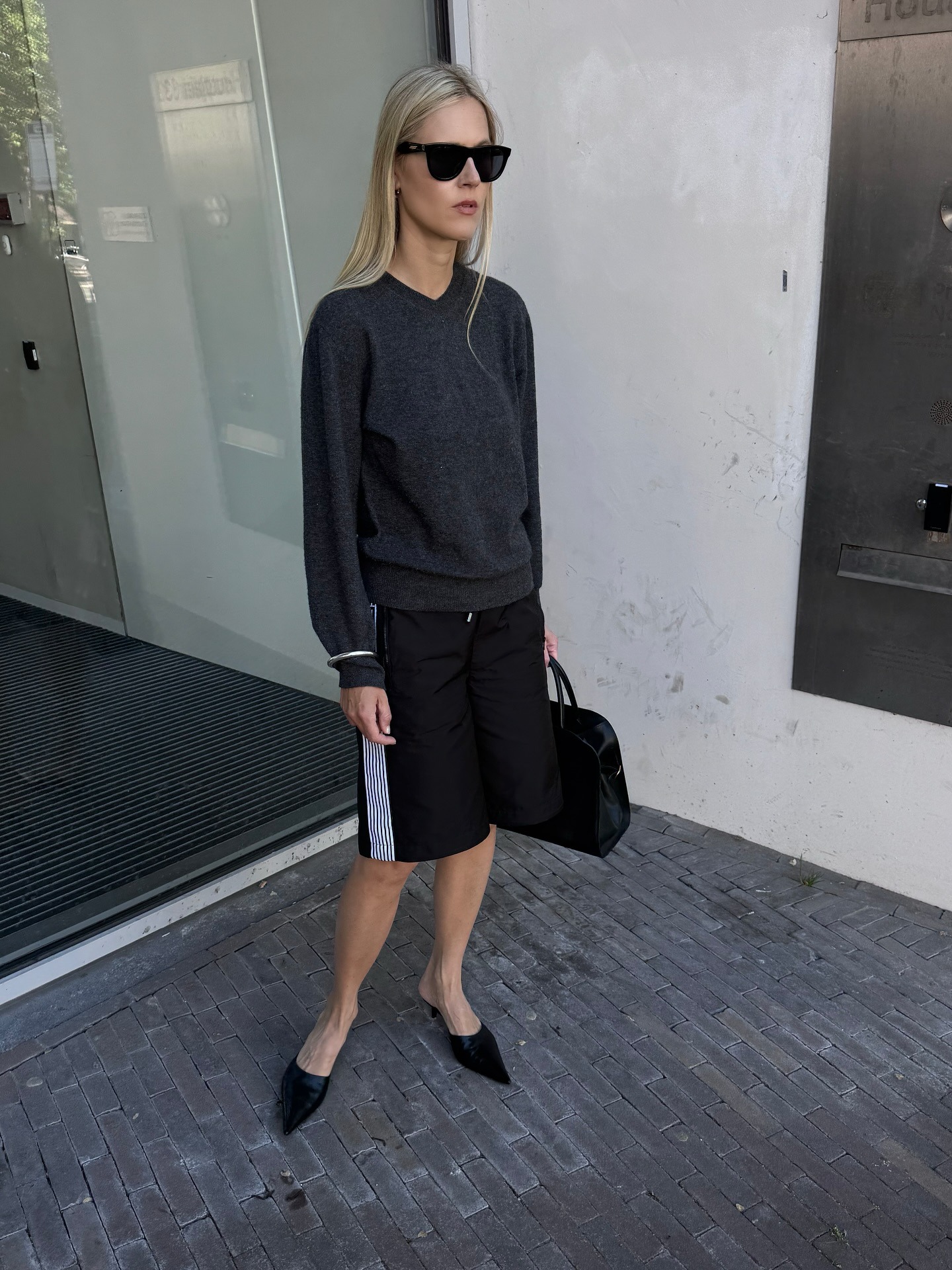 A woman wearing a black long sleeve shirt and black athletic shorts.