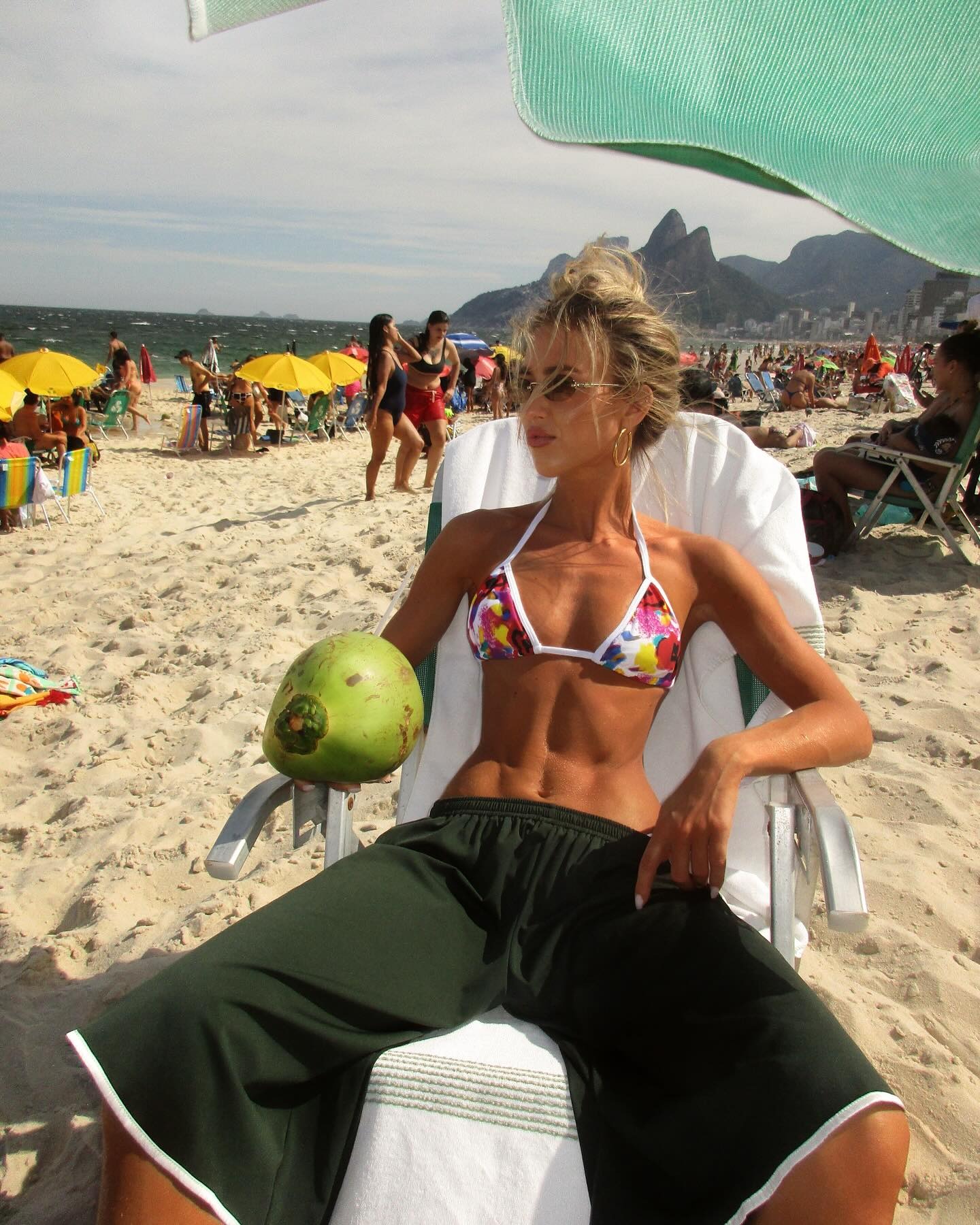 A woman wearing a bikini top and green athletic shorts.
