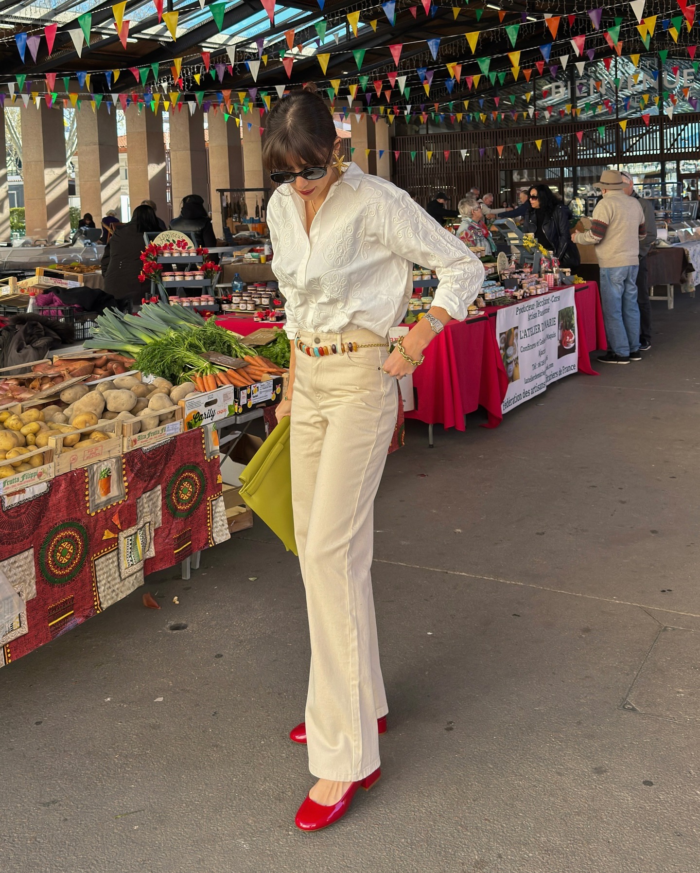Influencer @juliesfi wears beige flared jeans with red heeled pumps and a white shirt.