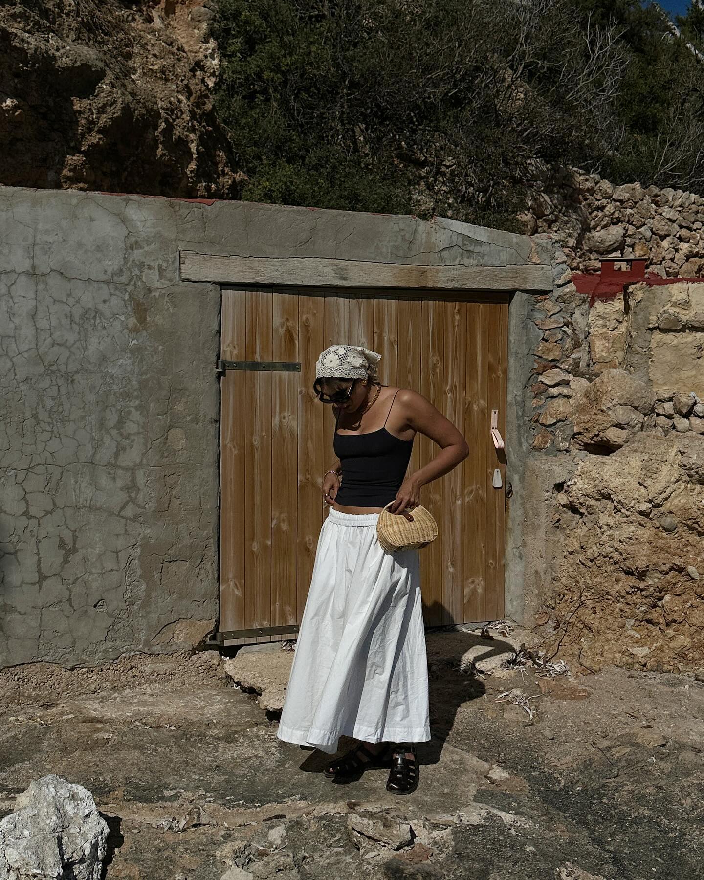 An image of @theindiaedit wearing fisherman sandals with a white cotton maxi skirt and black tank top.
