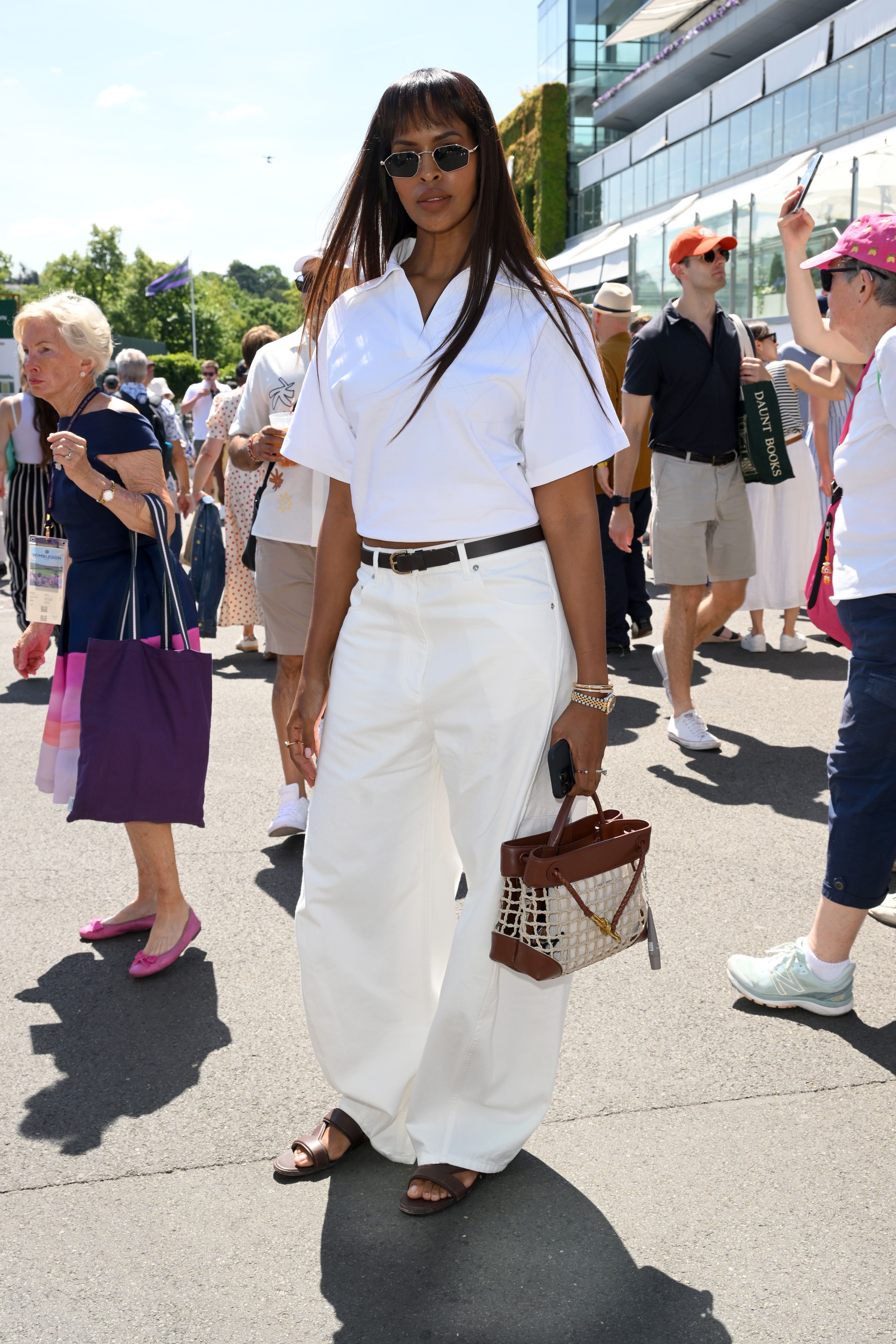 Sabrina Elba attends Wimbledon wearing white jeans with brown sandals and a brown belt.